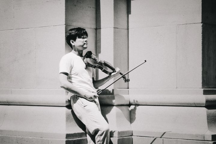 Siwoo Kim playing the violin against a stone wall