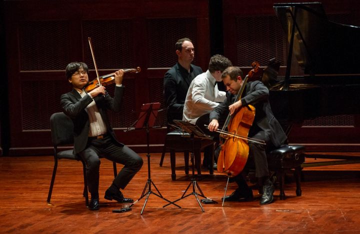 Siwoo Kim playing in a piano quartet on a dark wooden stage