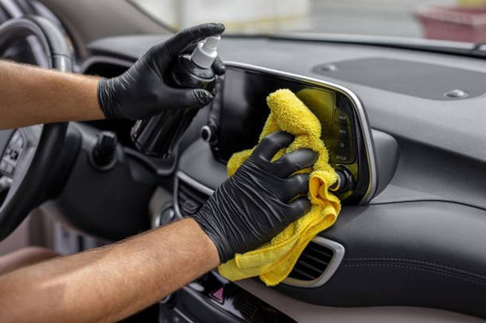 Detailer cleaning a car dashboard and centre console
