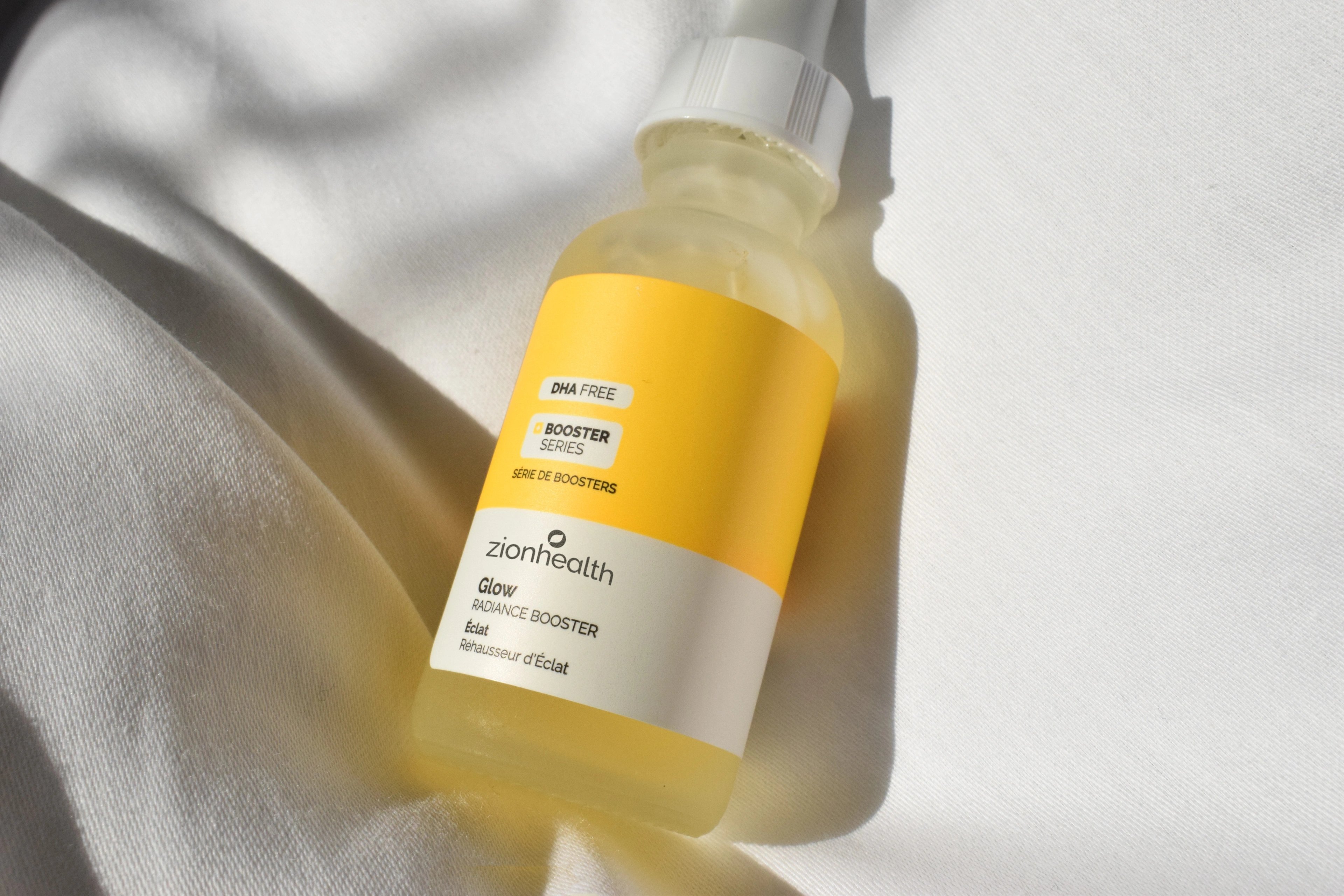 Zion Health serum in a yellow dropper bottle resting on softly draped fabric
