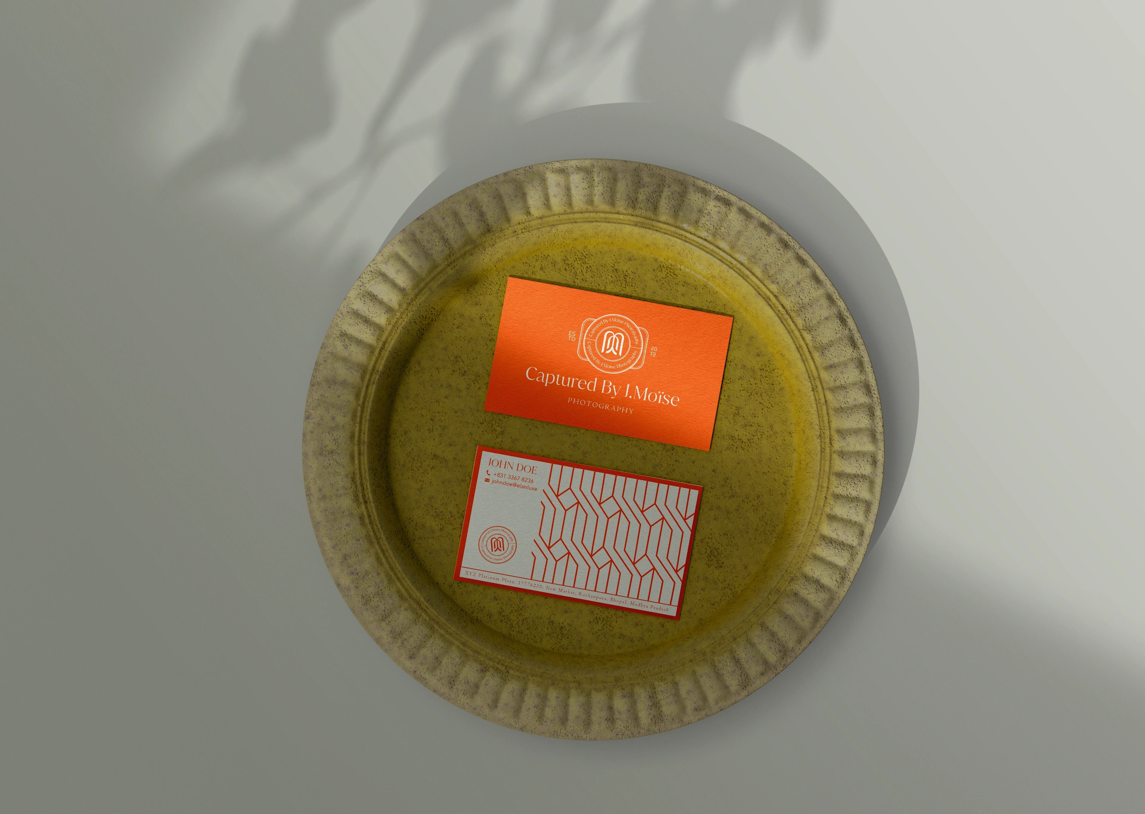Captured by J. Moïse business cards — a burnt-orange card and a patterned card on a textured surface