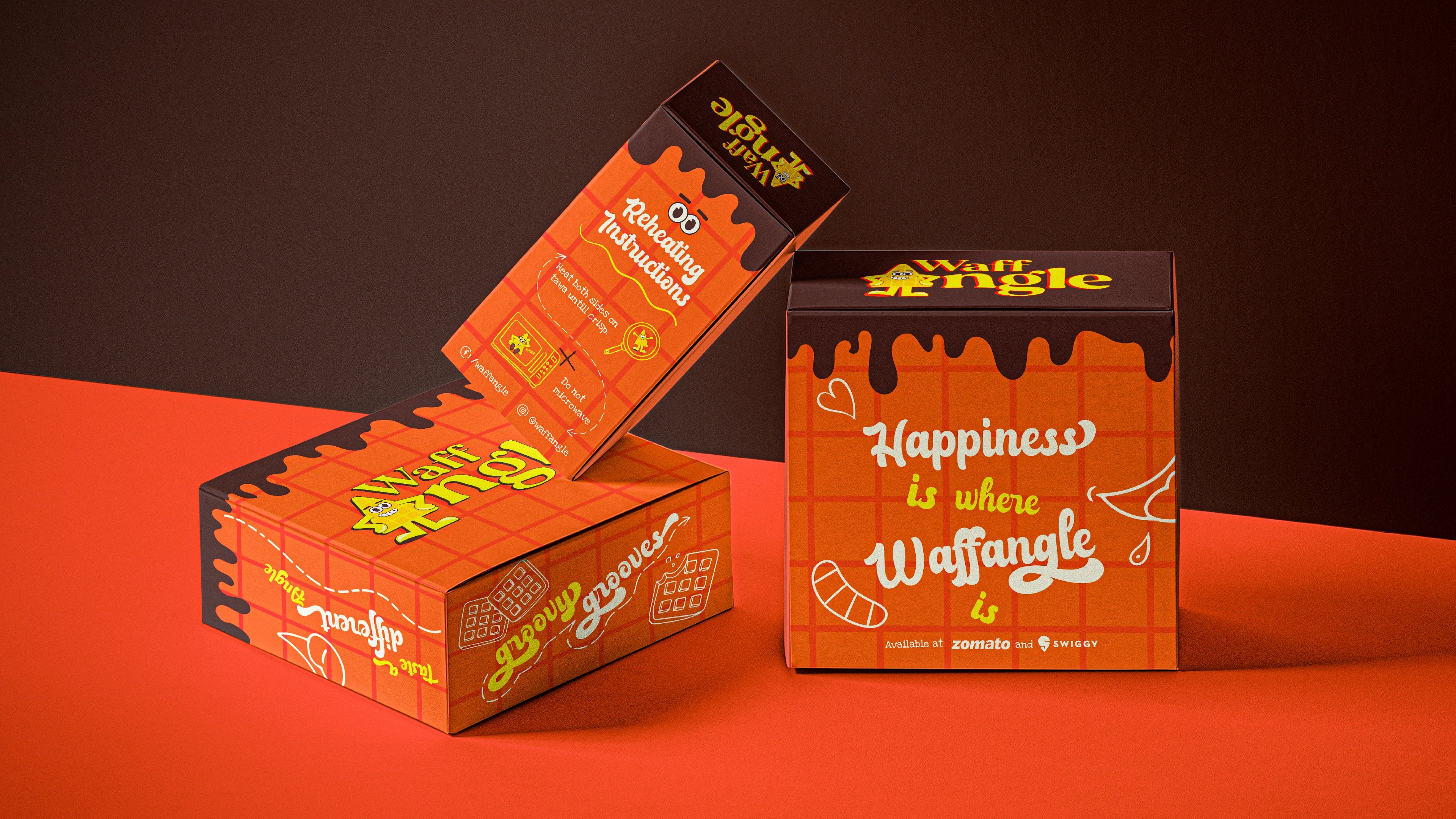Waffangle takeaway boxes reading 'Happiness is when' stacked on an orange surface
