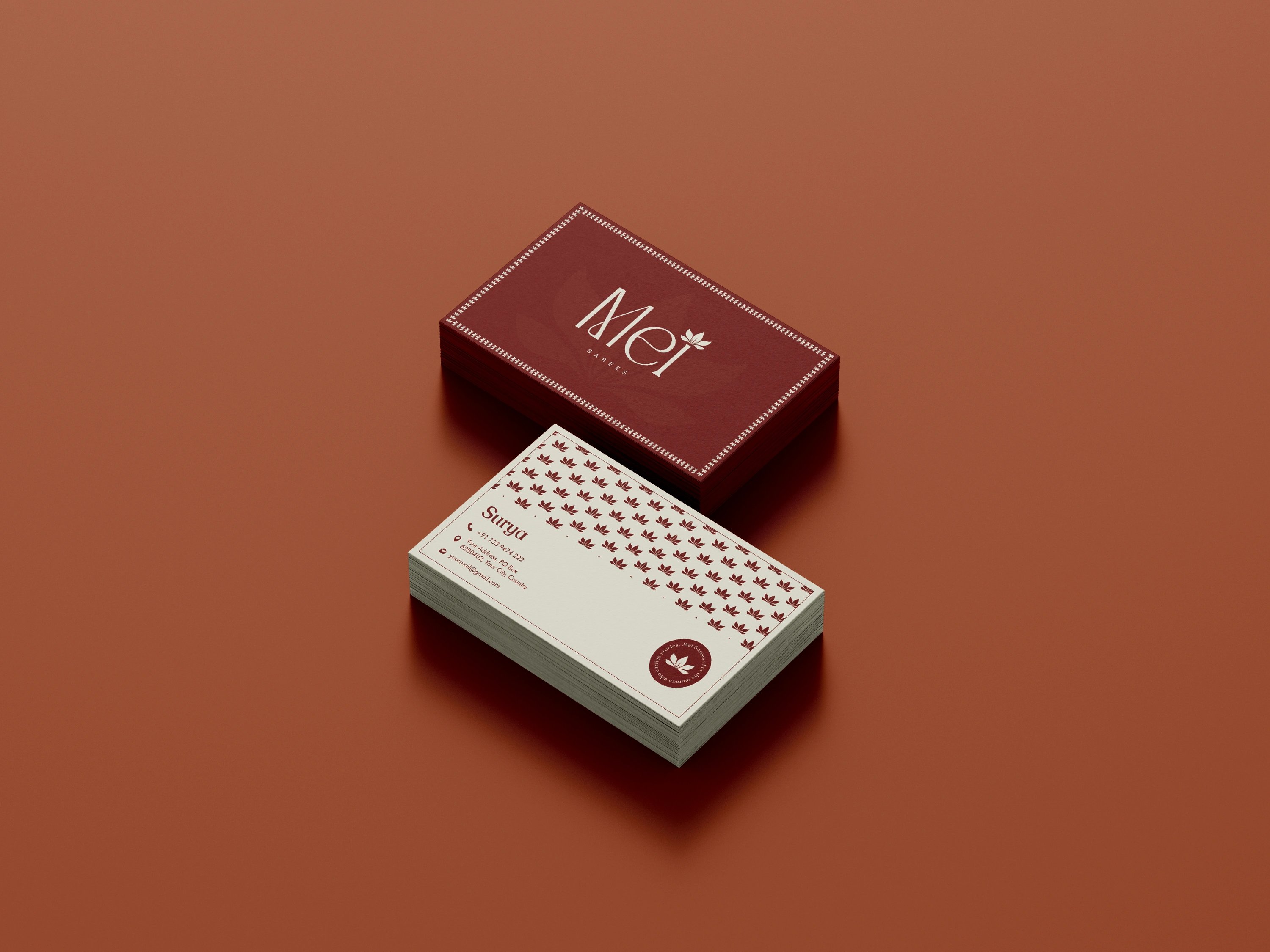 Mei business cards in maroon with a lotus pattern, on clay