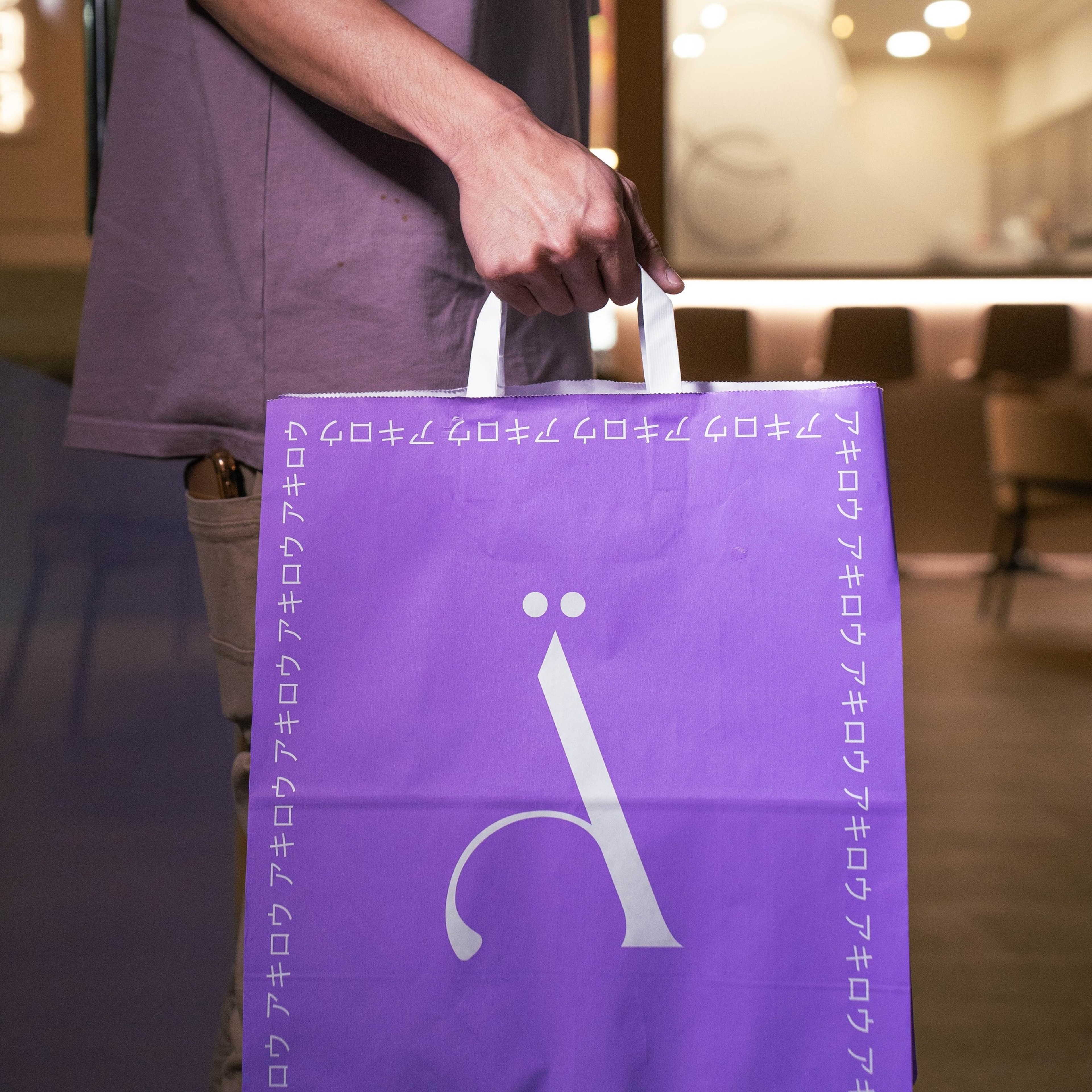 Customer holding a purple ÄKIRO shopping bag with the Ä icon