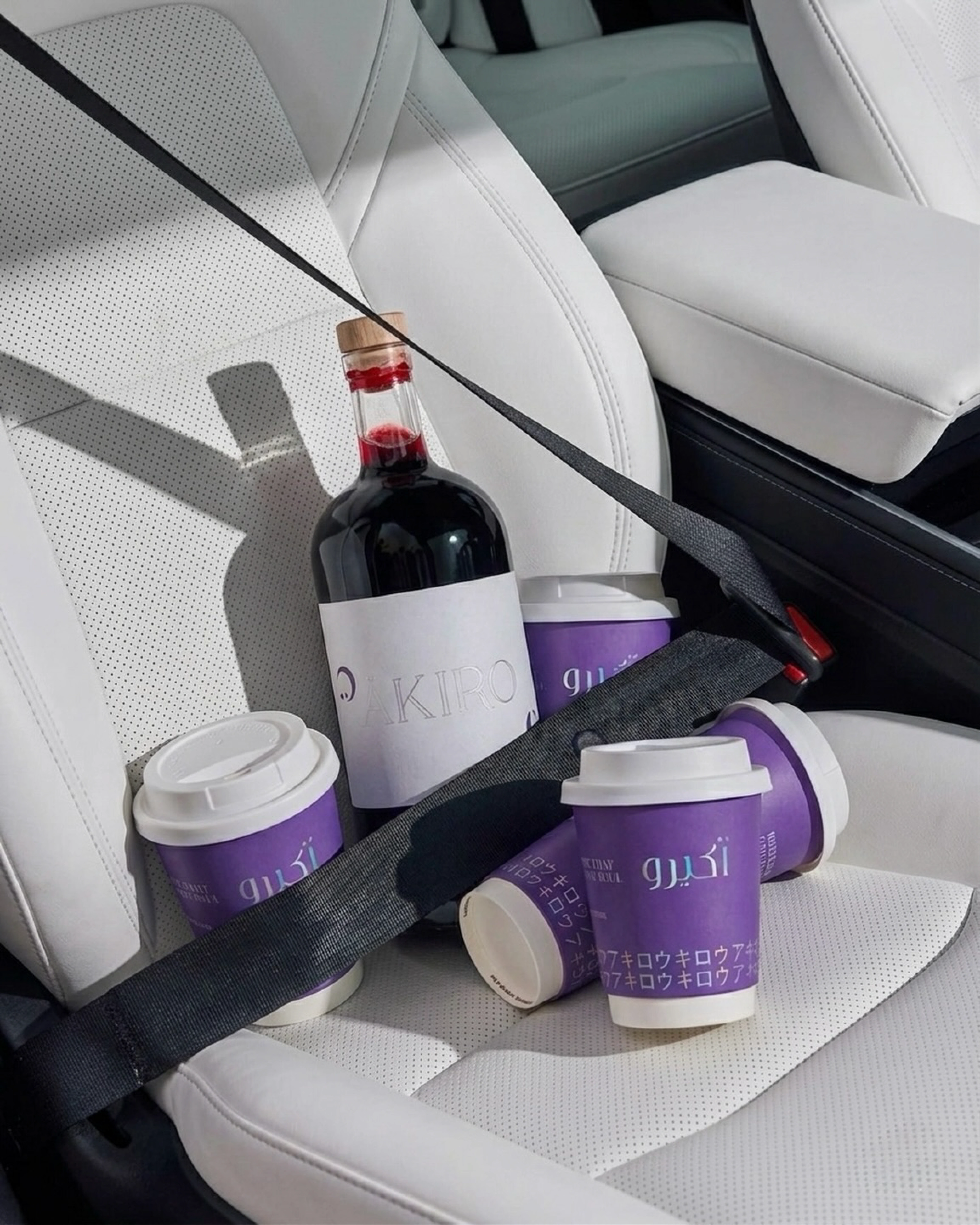 ÄKIRO cups and a branded bottle on a car seat, a to-go moment