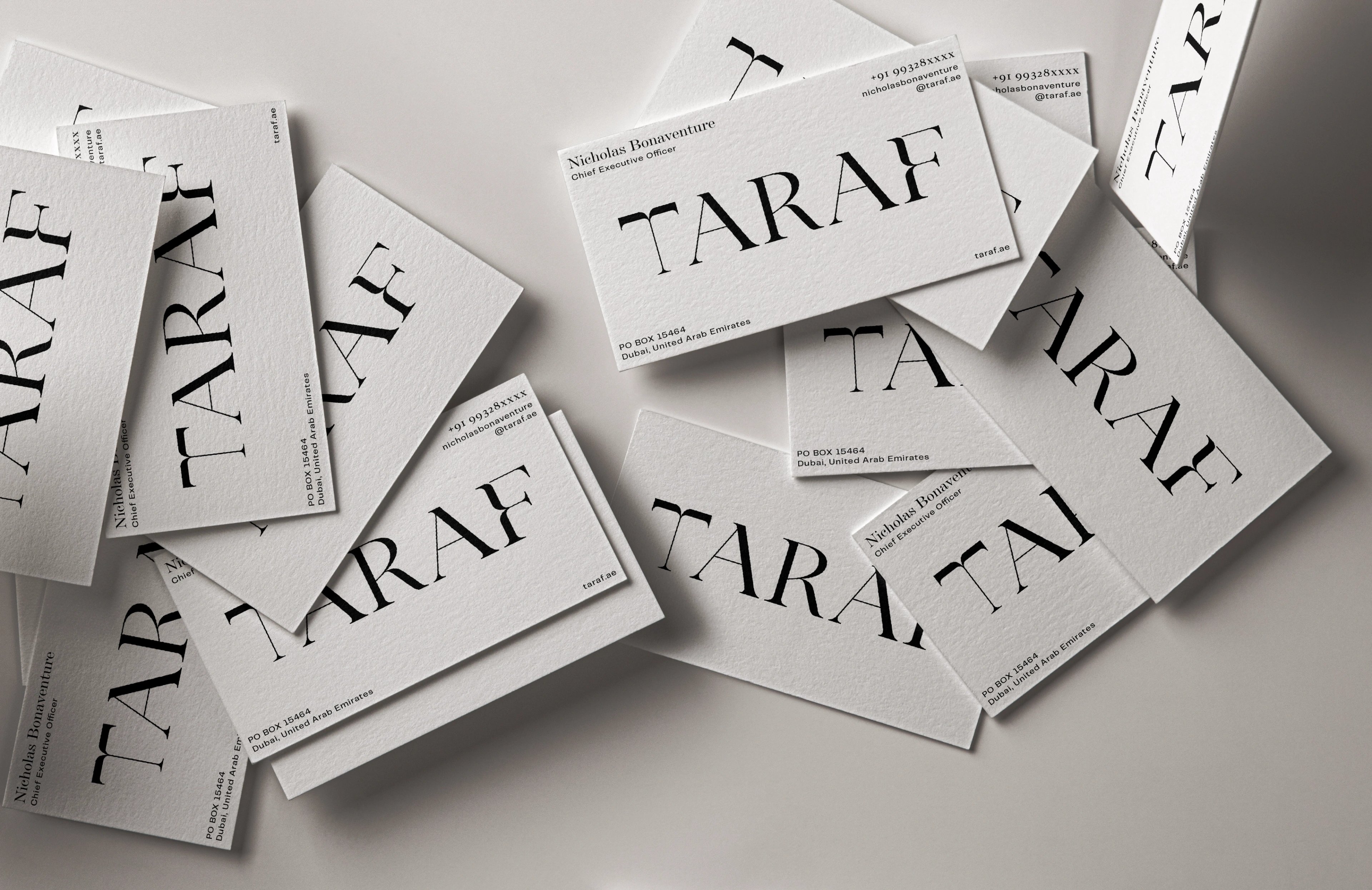 Scattered Taraf business cards spread across a grey surface