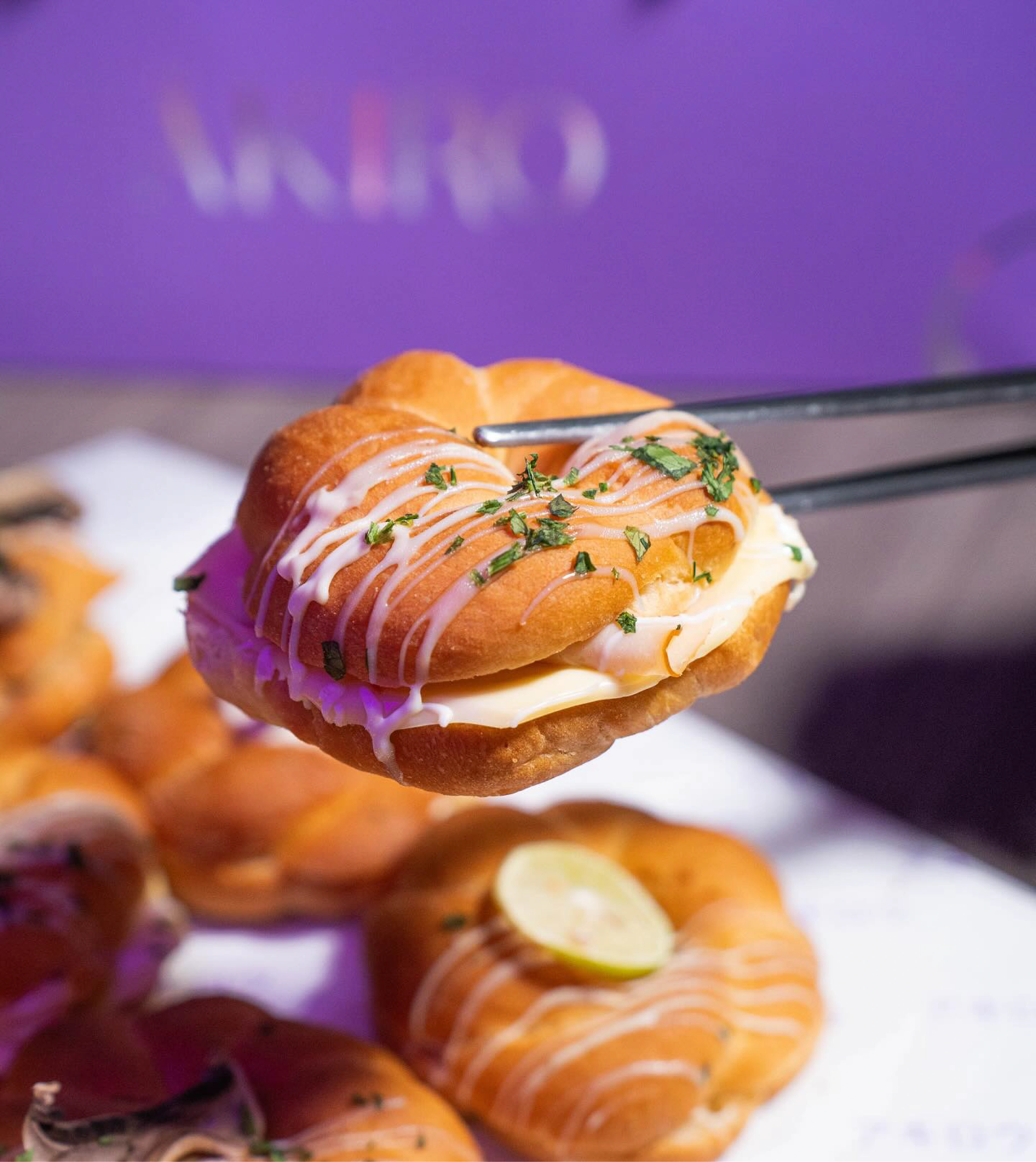 Tweezers placing a garnish on a cream-filled ÄKIRO pastry