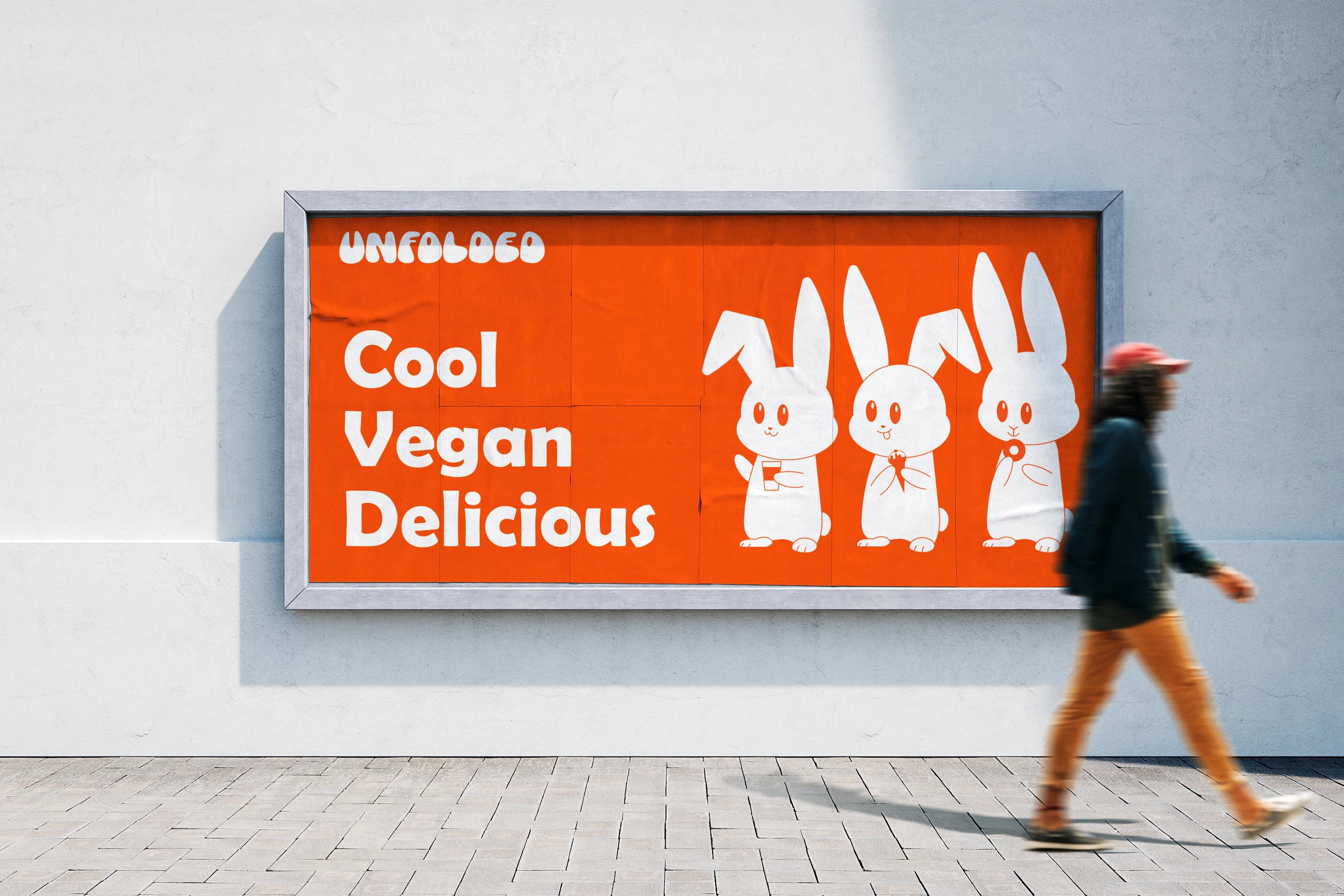 UNFOLDED 'Cool Vegan Delicious' billboard with three bunnies on a city wall as a pedestrian walks past