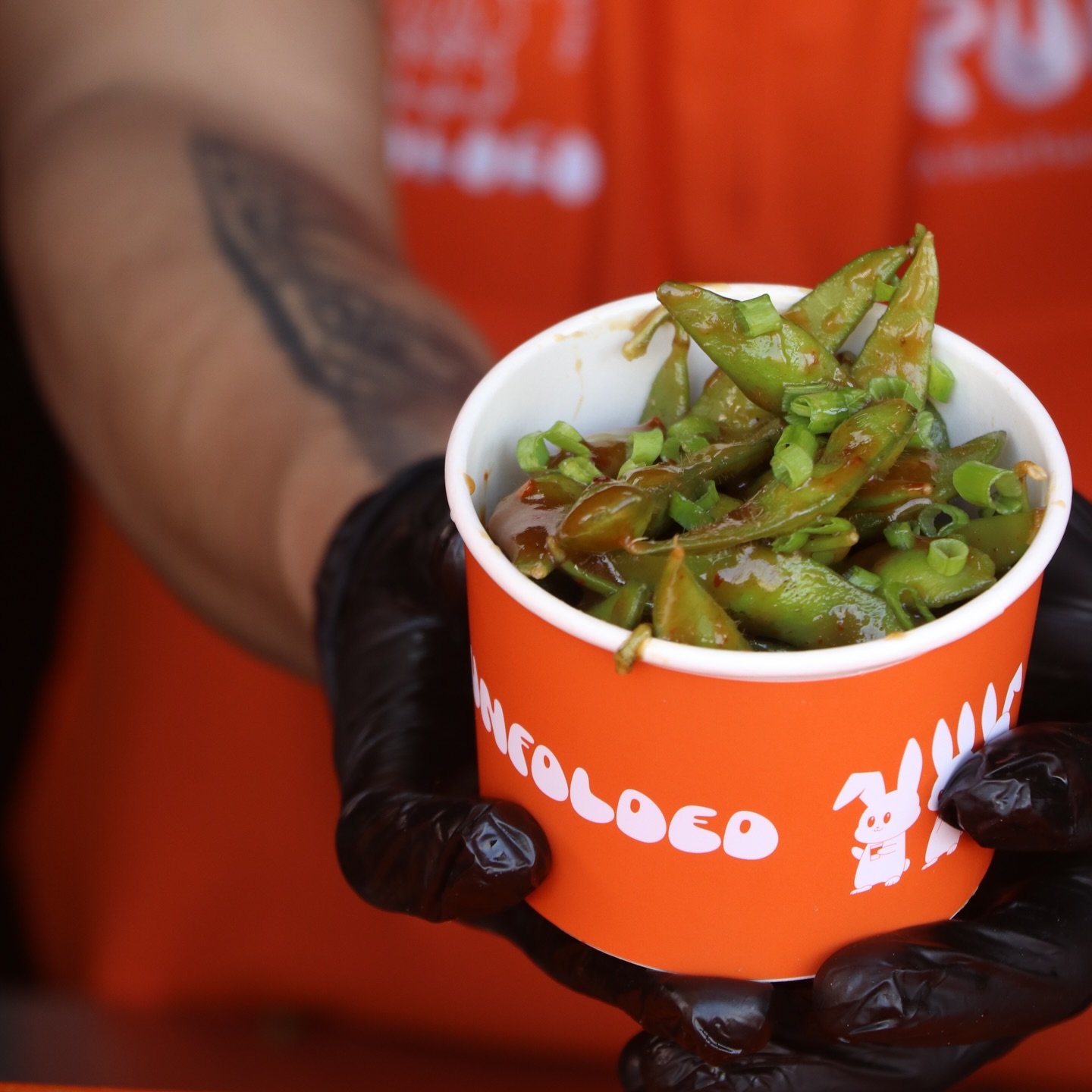 PULL cup of chilli-garlic edamame on a bold orange surface