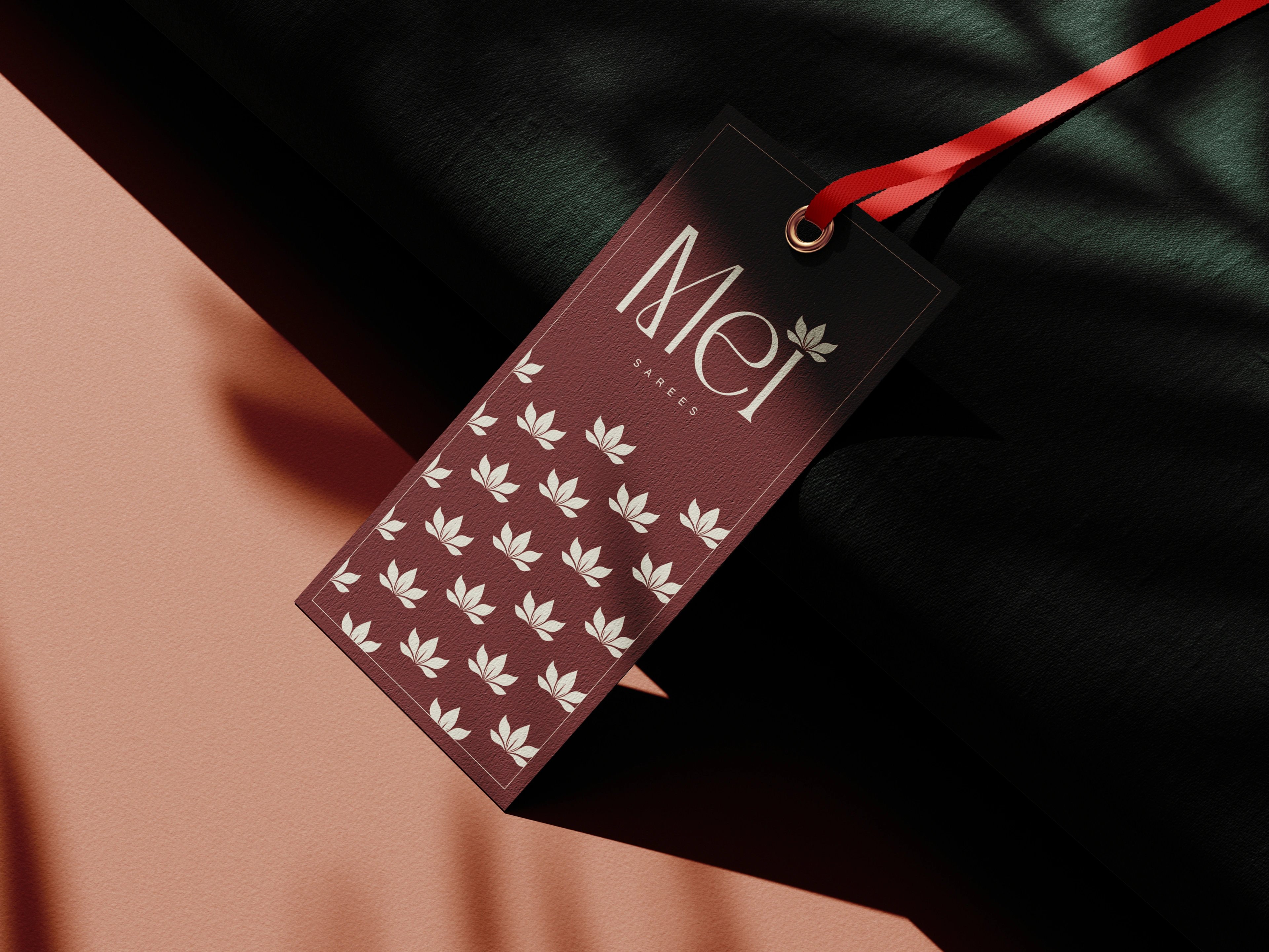 Mei hang tag front in maroon with a red ribbon and lotus pattern