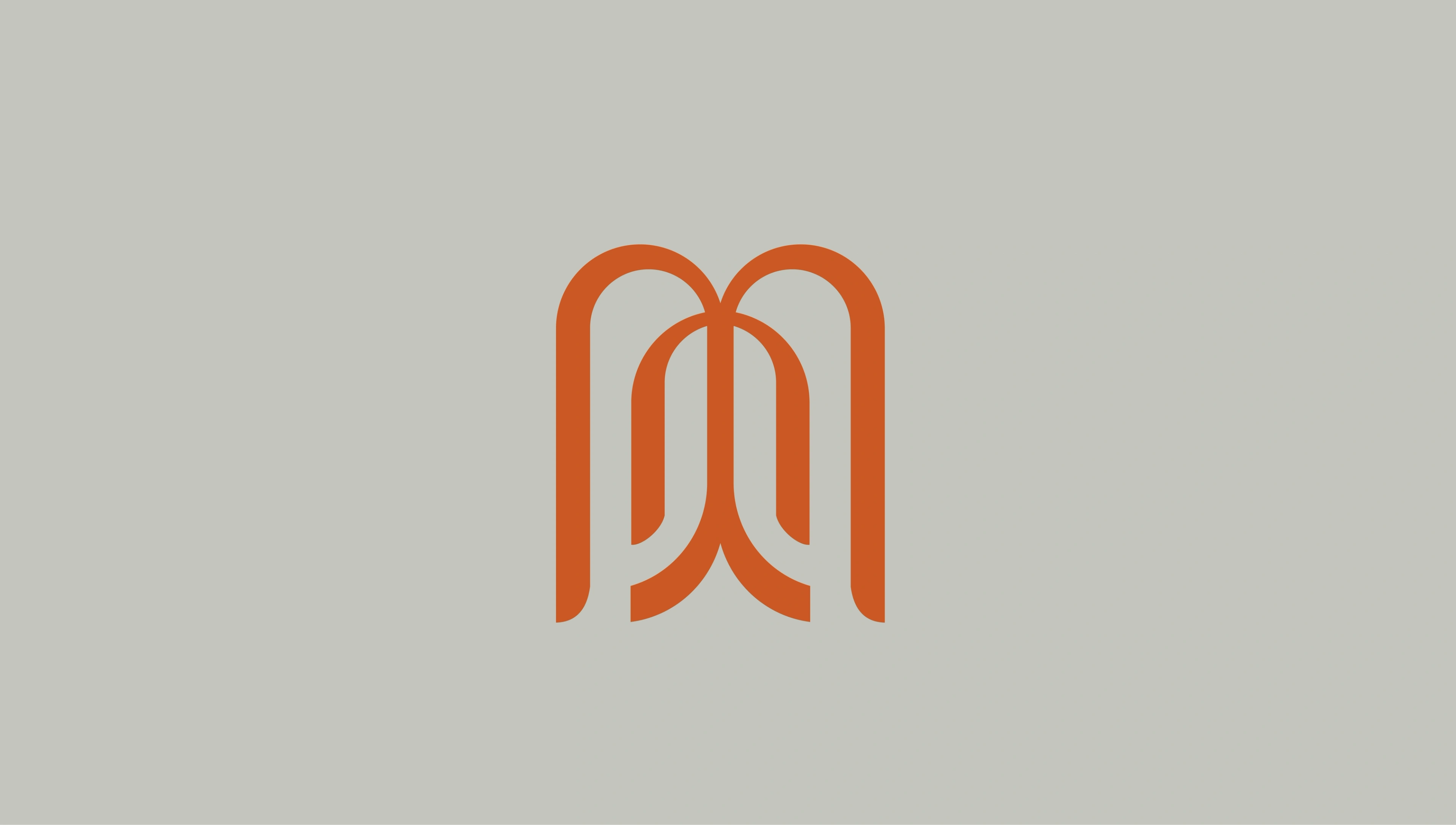 the Captured by J. Moïse monogram — interlocking arches forming the studio's initials in burnt orange on sage-grey
