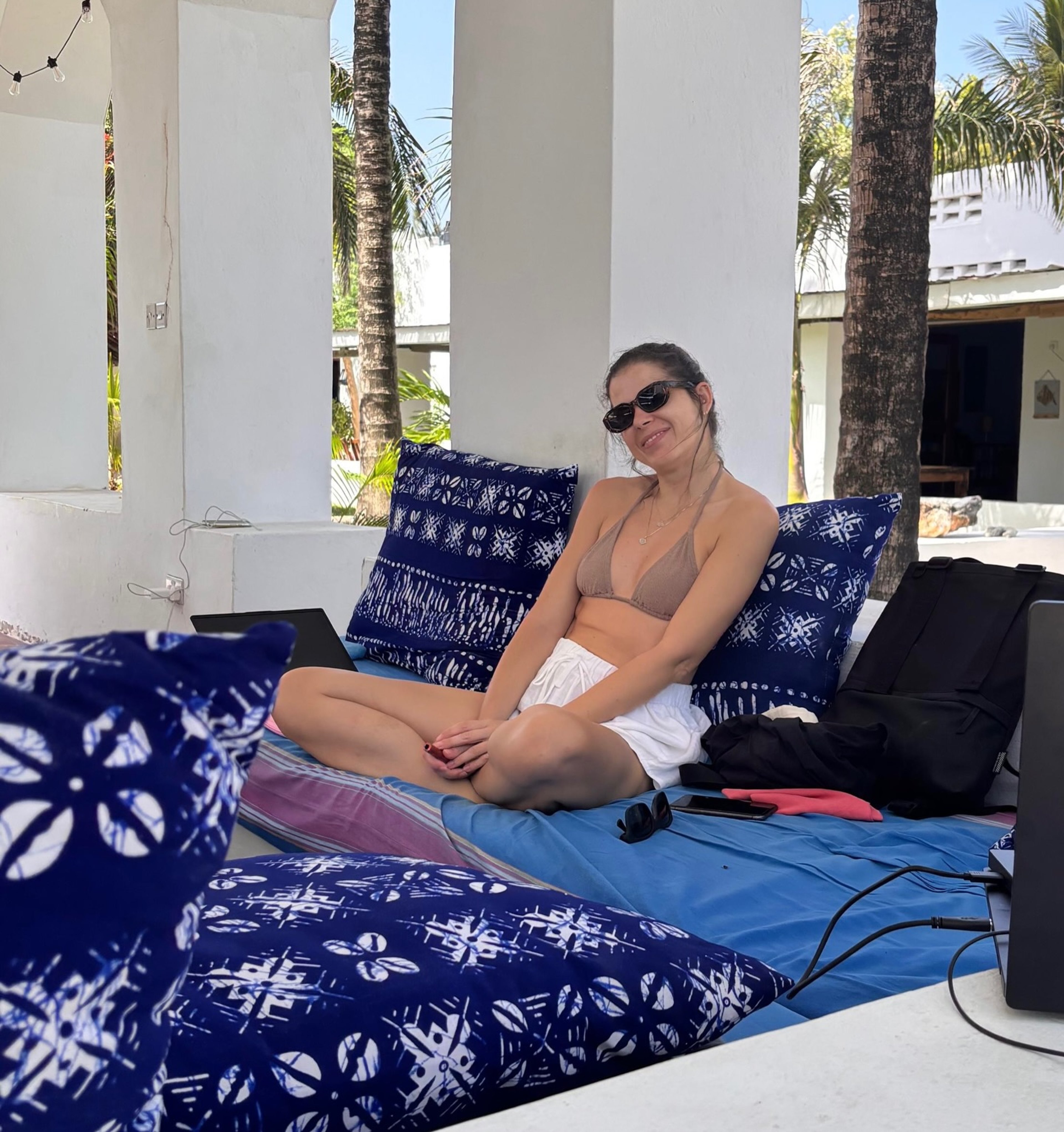 A guest relaxing on a daybed piled with indigo African-print cushions on the Sawa Sawa pool terrace