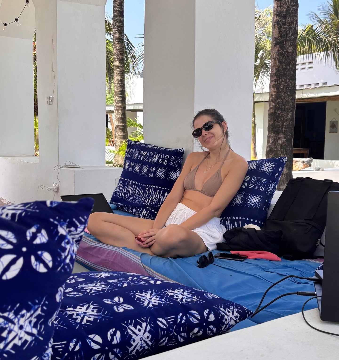 A guest relaxing on a daybed piled with indigo African-print cushions on the Sawa Sawa pool terrace