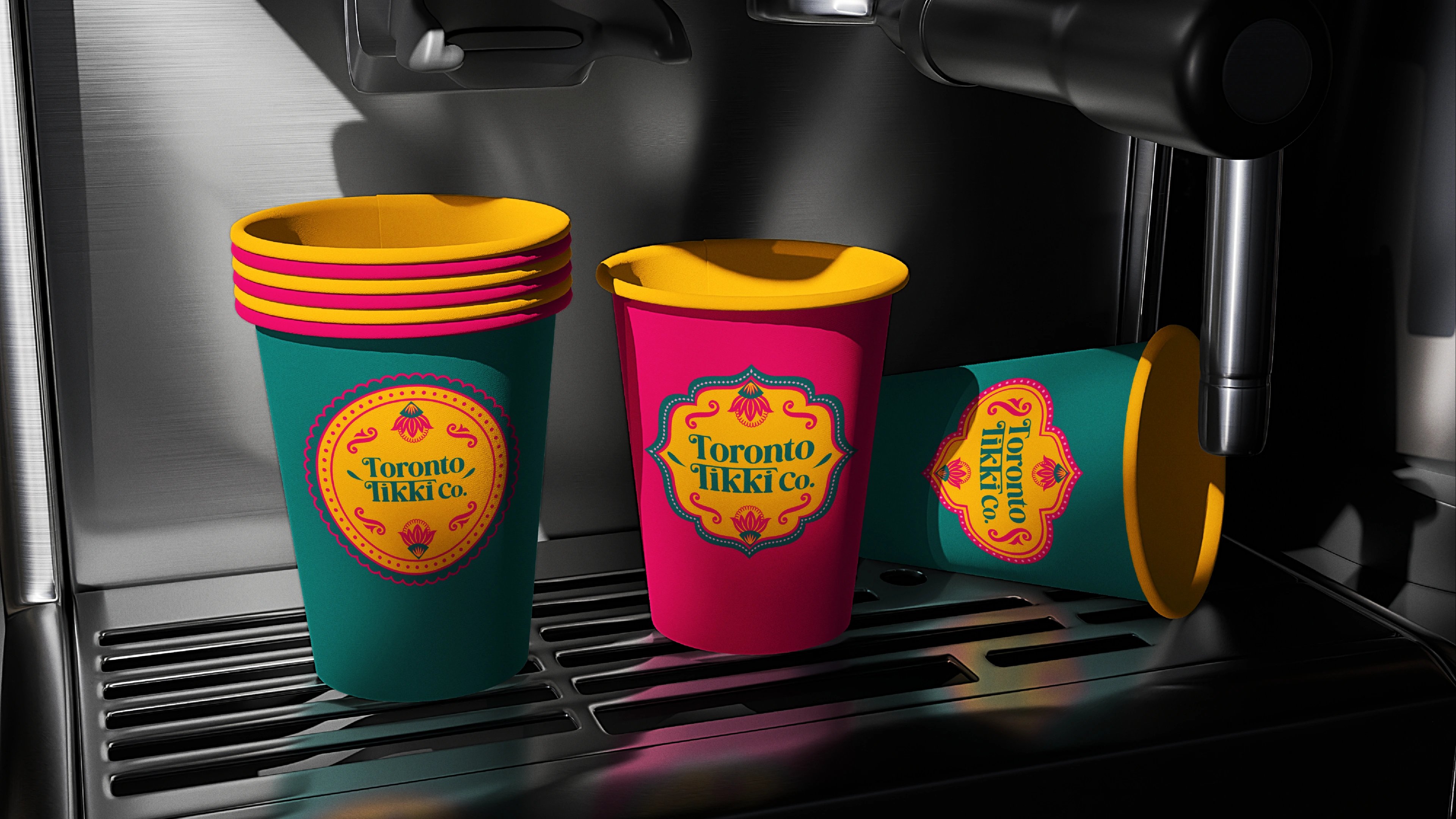 Two Toronto Tikki Co. branded takeaway cups in teal and magenta on a counter