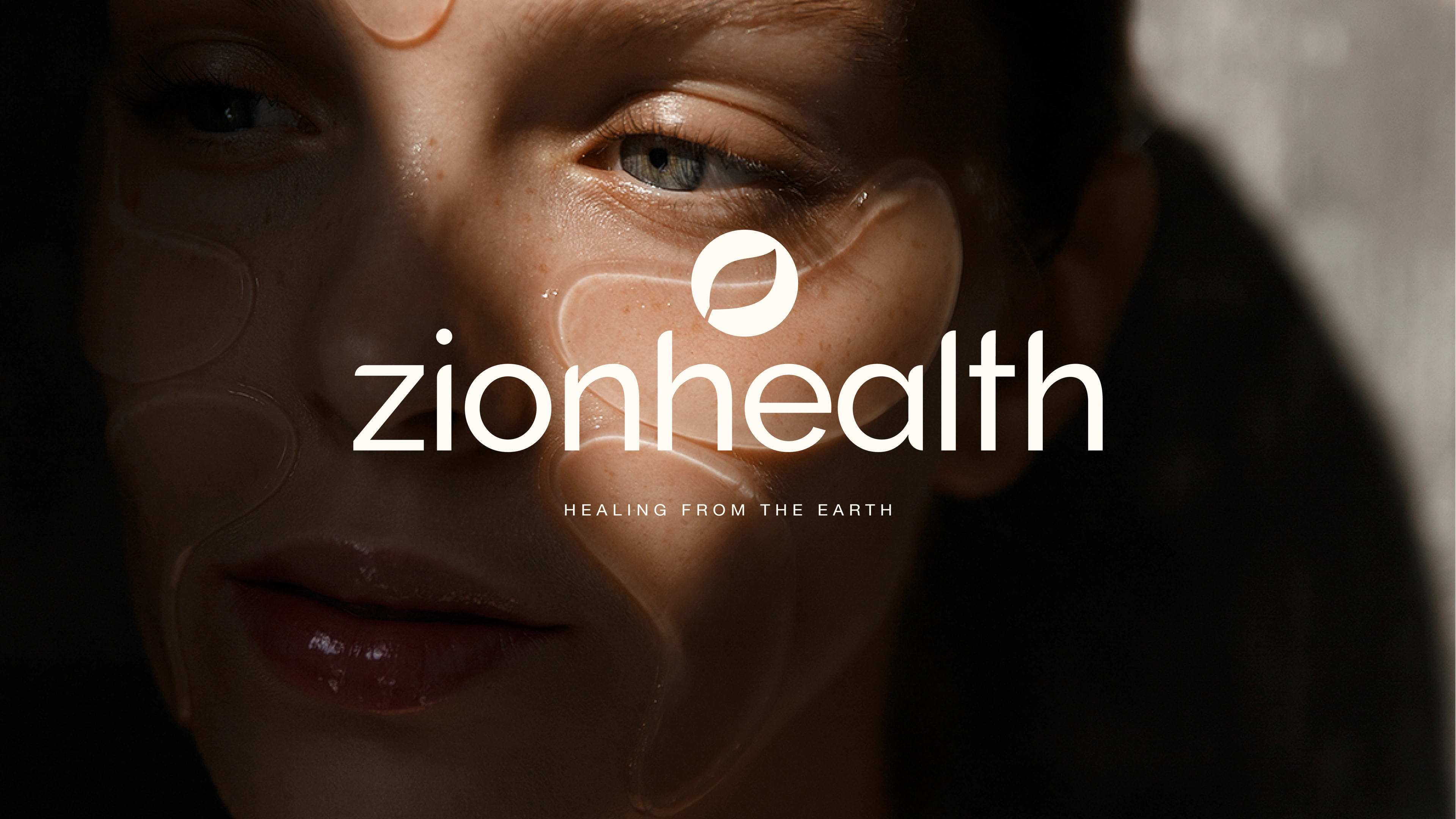 Zion Health brand portrait — the zionhealth wordmark and healing-from-the-earth tagline set over a low-lit portrait