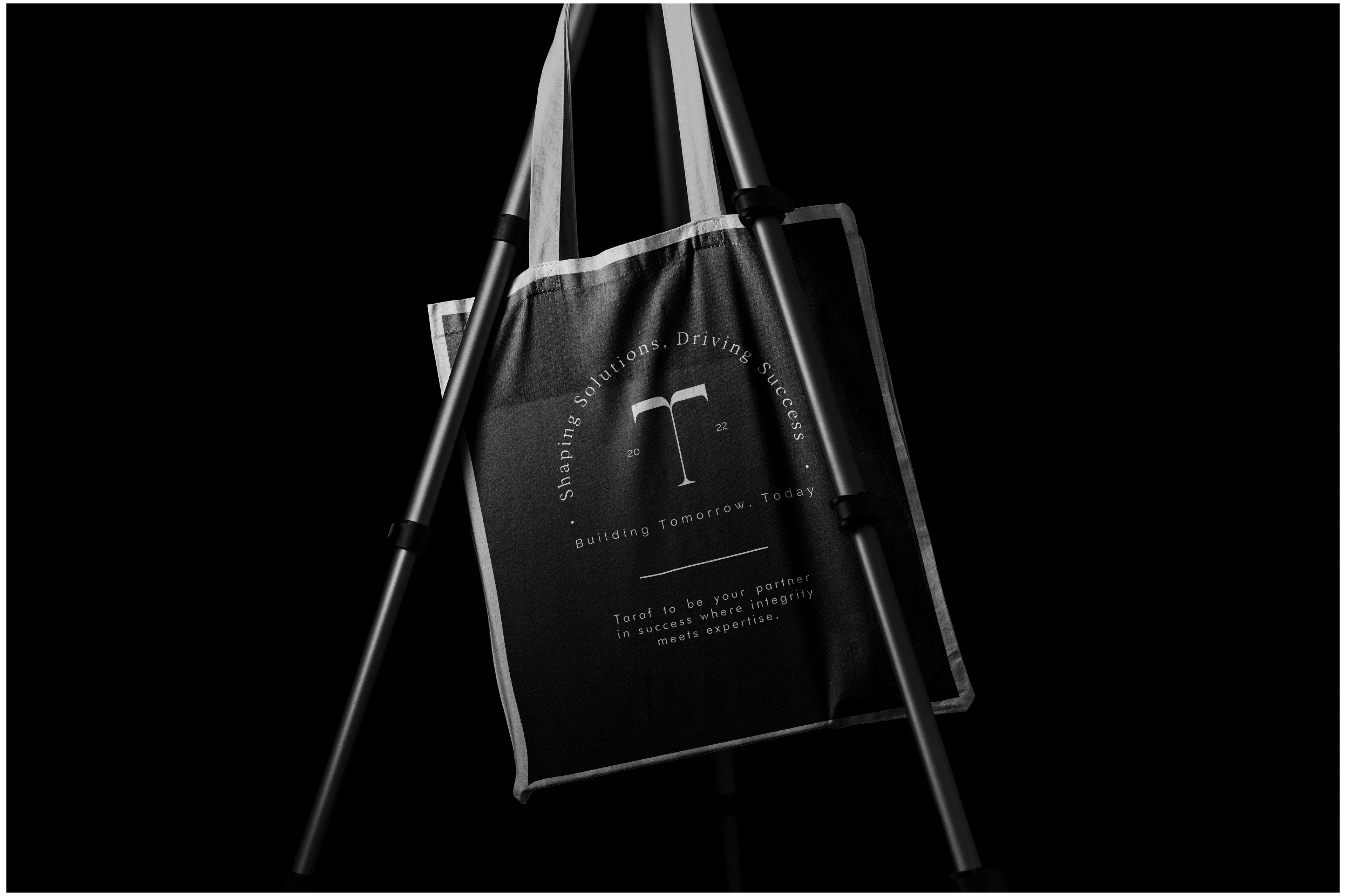 Black Taraf tote bag with the emblem and tagline on a stand