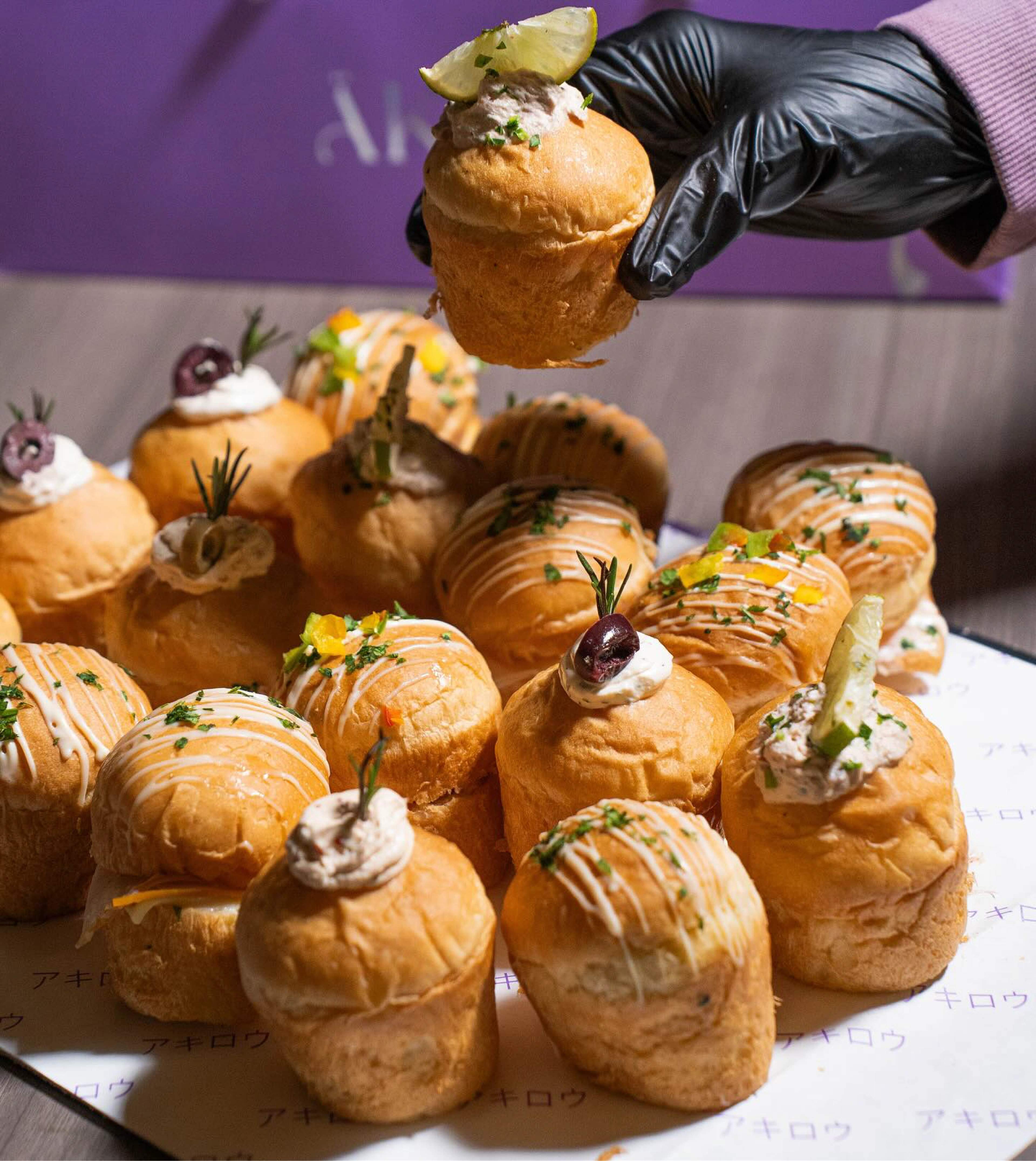 Gloved hand arranging garnished choux pastries on an ÄKIRO tray