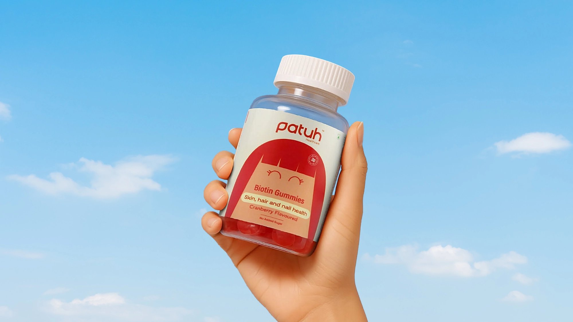 Hand holding a Patuh supplement bottle against a sky background