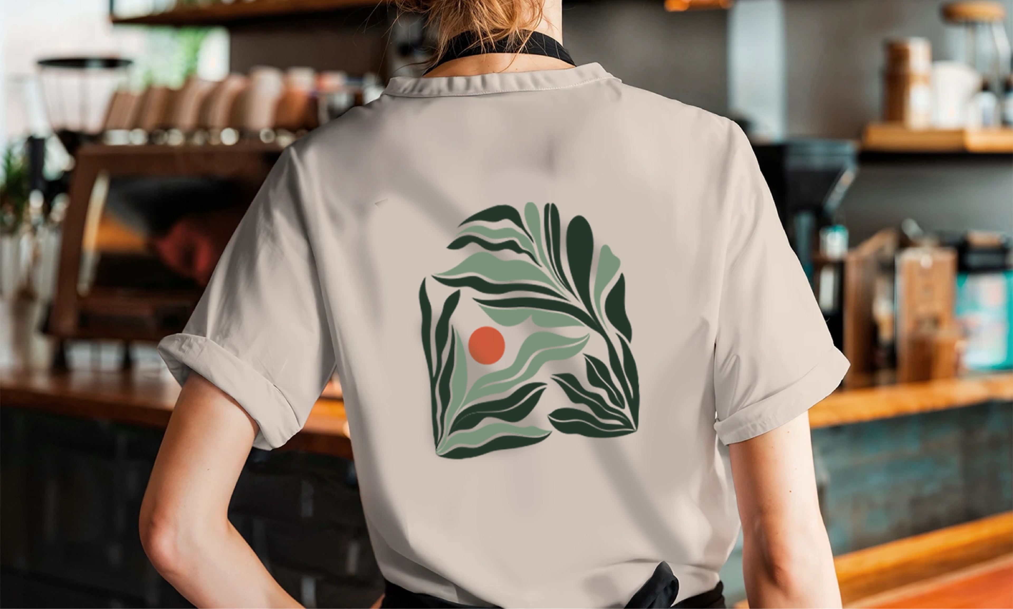 Barista in a Drip Happens staff tee printed with the leaf monogram, inside the New Cairo café