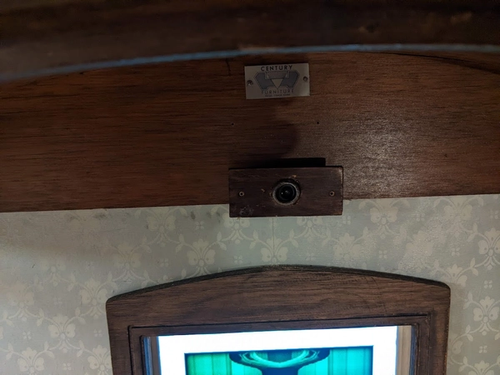 Webcam with wooden surround above a framed vertical screen.