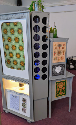 cabinet showing screen, lit underneath with various holes and images attached to the sides.