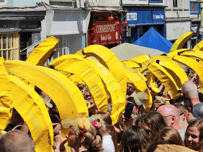 Lots of giant paper maché bananas surrounded  by onlookers