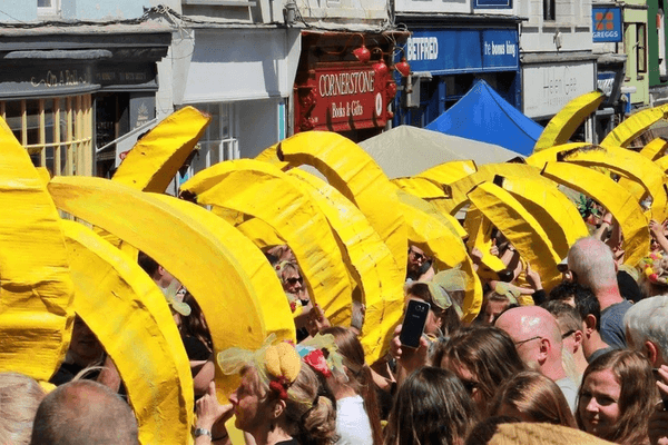Lots of giant paper maché bananas surrounded  by onlookers