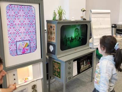 Child looking at large vertical screen showing kaleidoscope image of drawing.