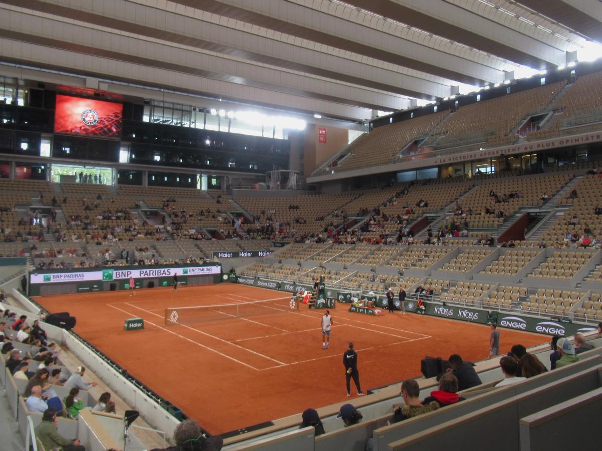 A match on the red clay of Court Philippe-Chatrier, with the stands under its roof structure