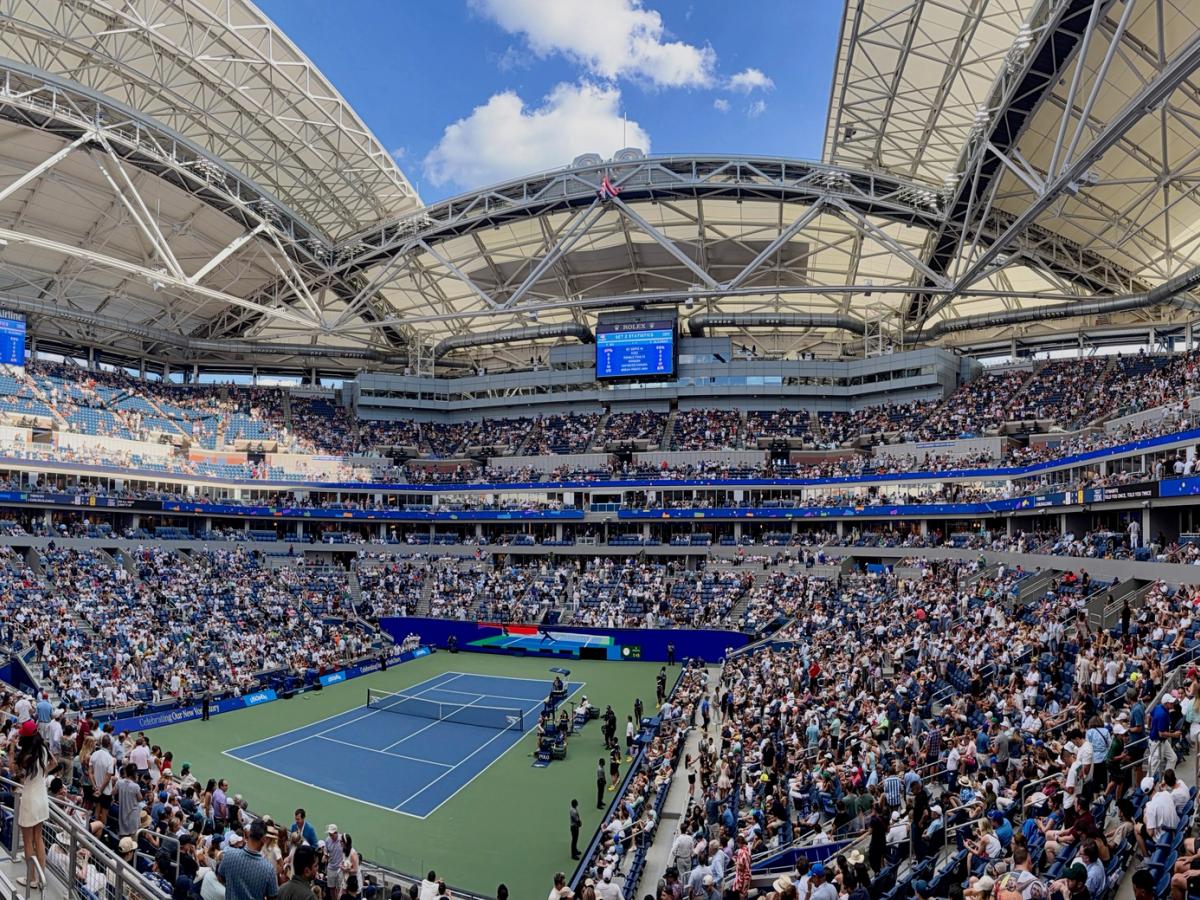 Panorama of a crowded Arthur Ashe Stadium during a match, with the roof open
