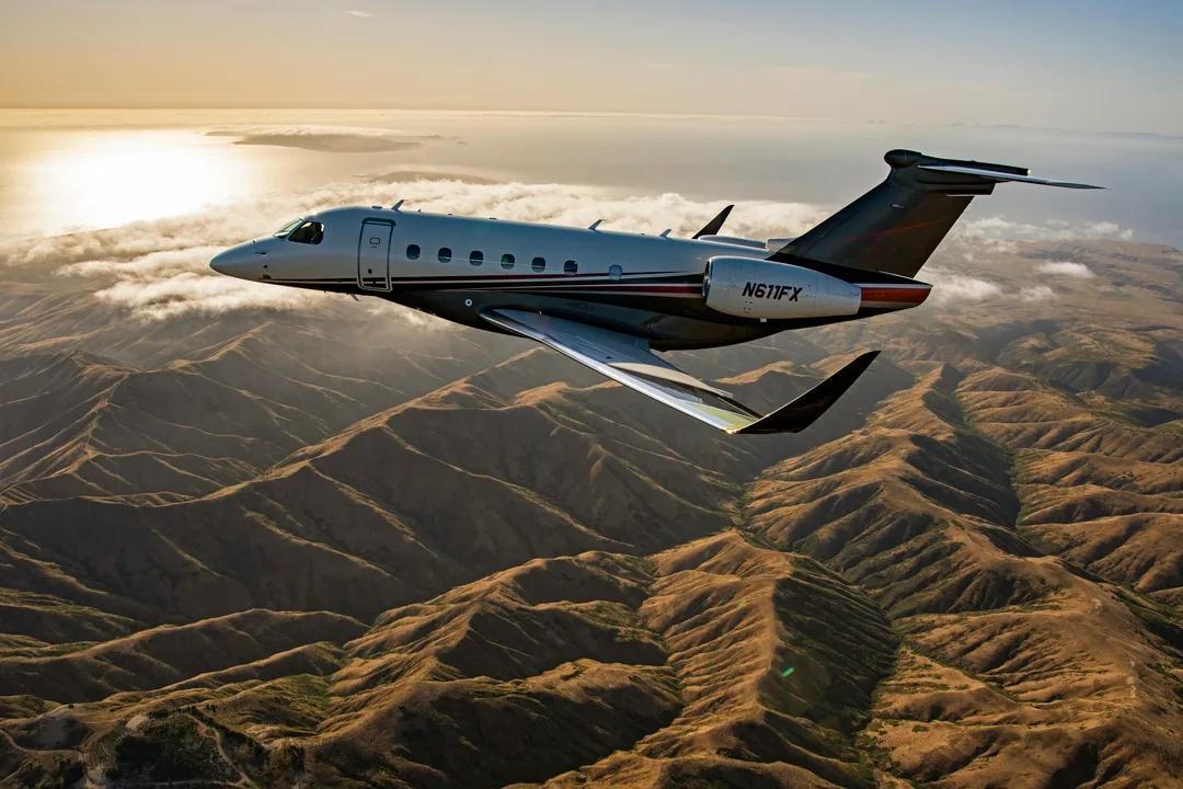 Embraer Praetor 600E in Flexjet livery flying above mountain ridges and low cloud.