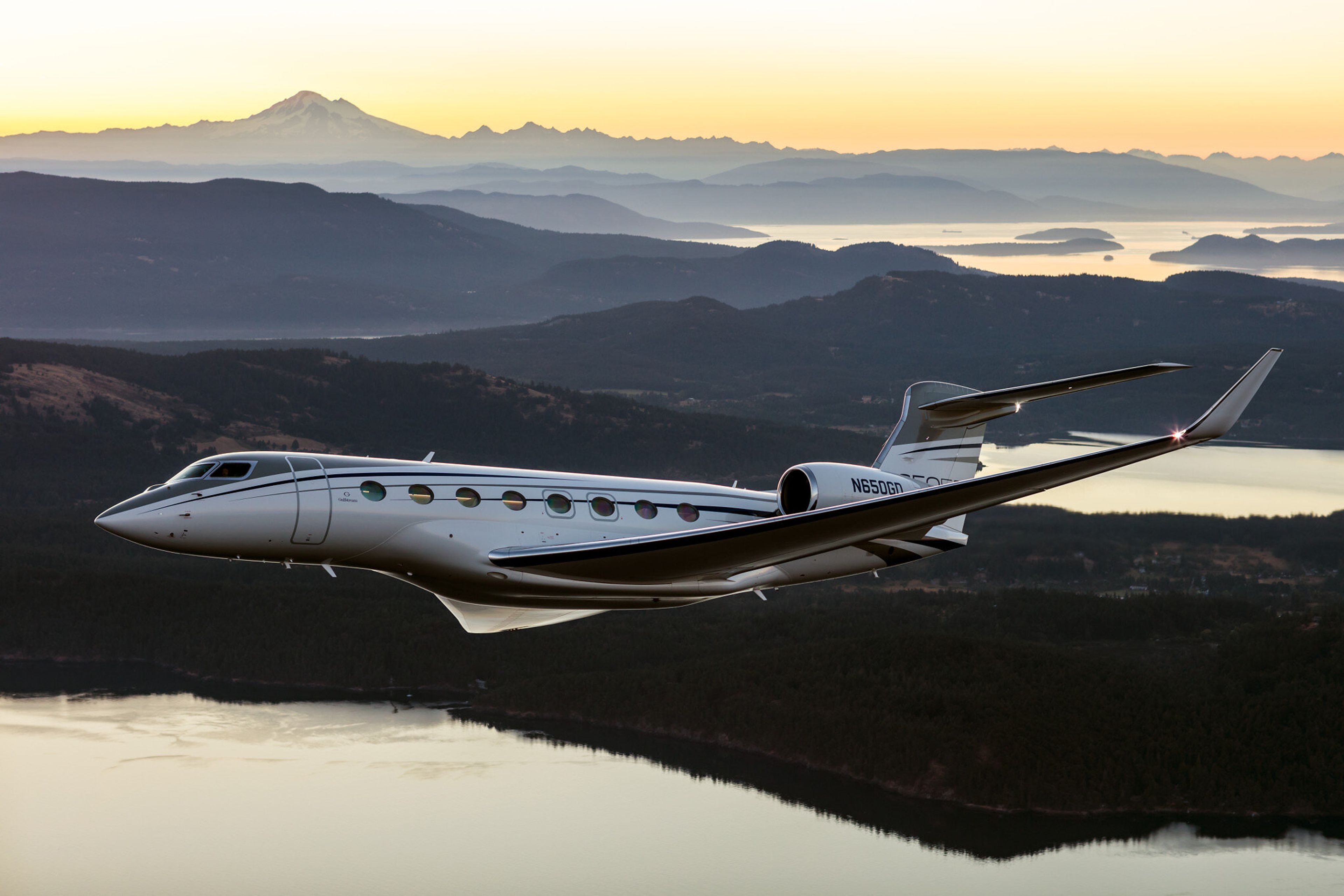 Gulfstream G650ER flying above mountains at sunset
