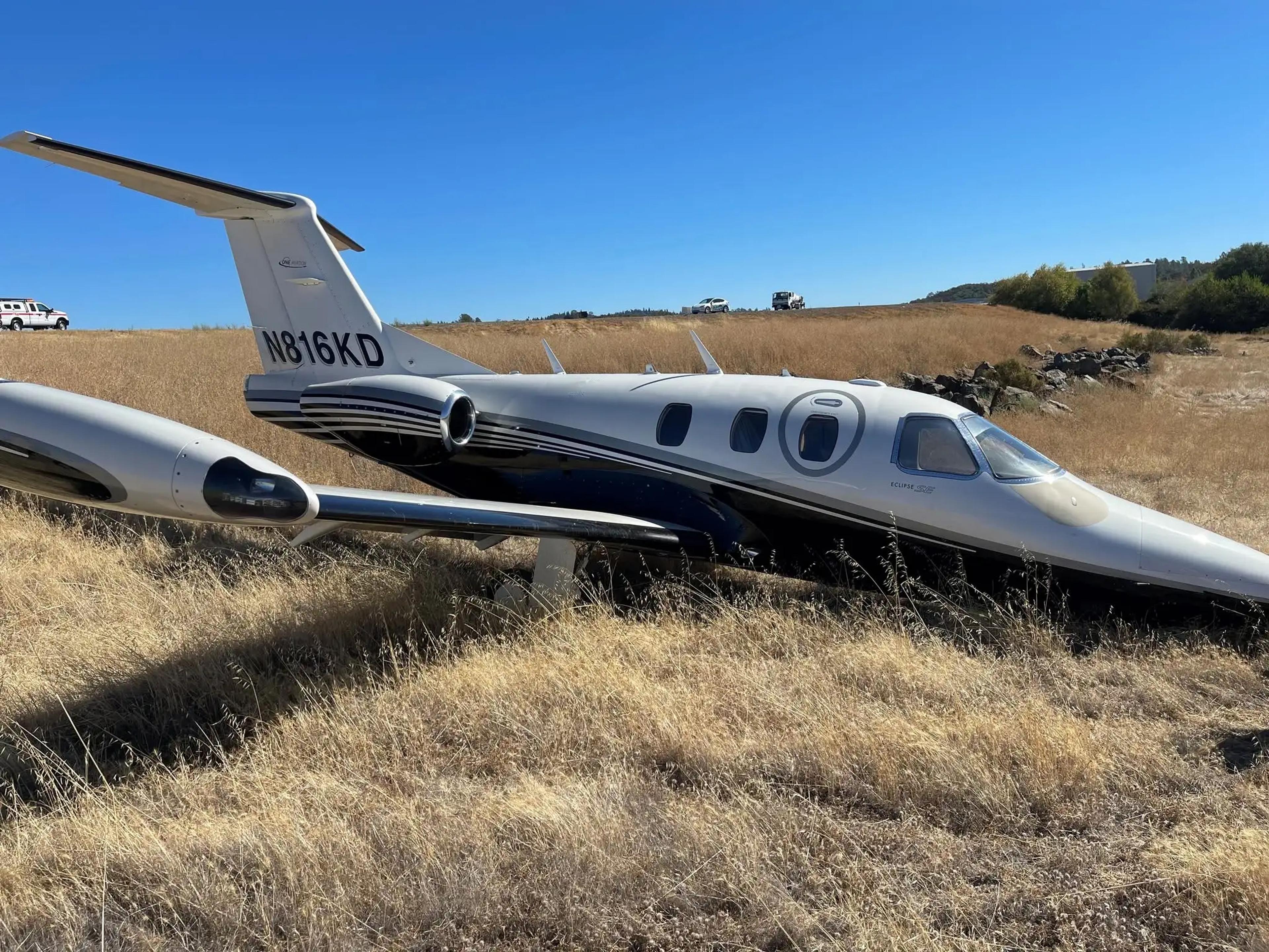 Eclipse 500 N816KD resting in dry grass beyond the runway at Auburn Municipal Airport.