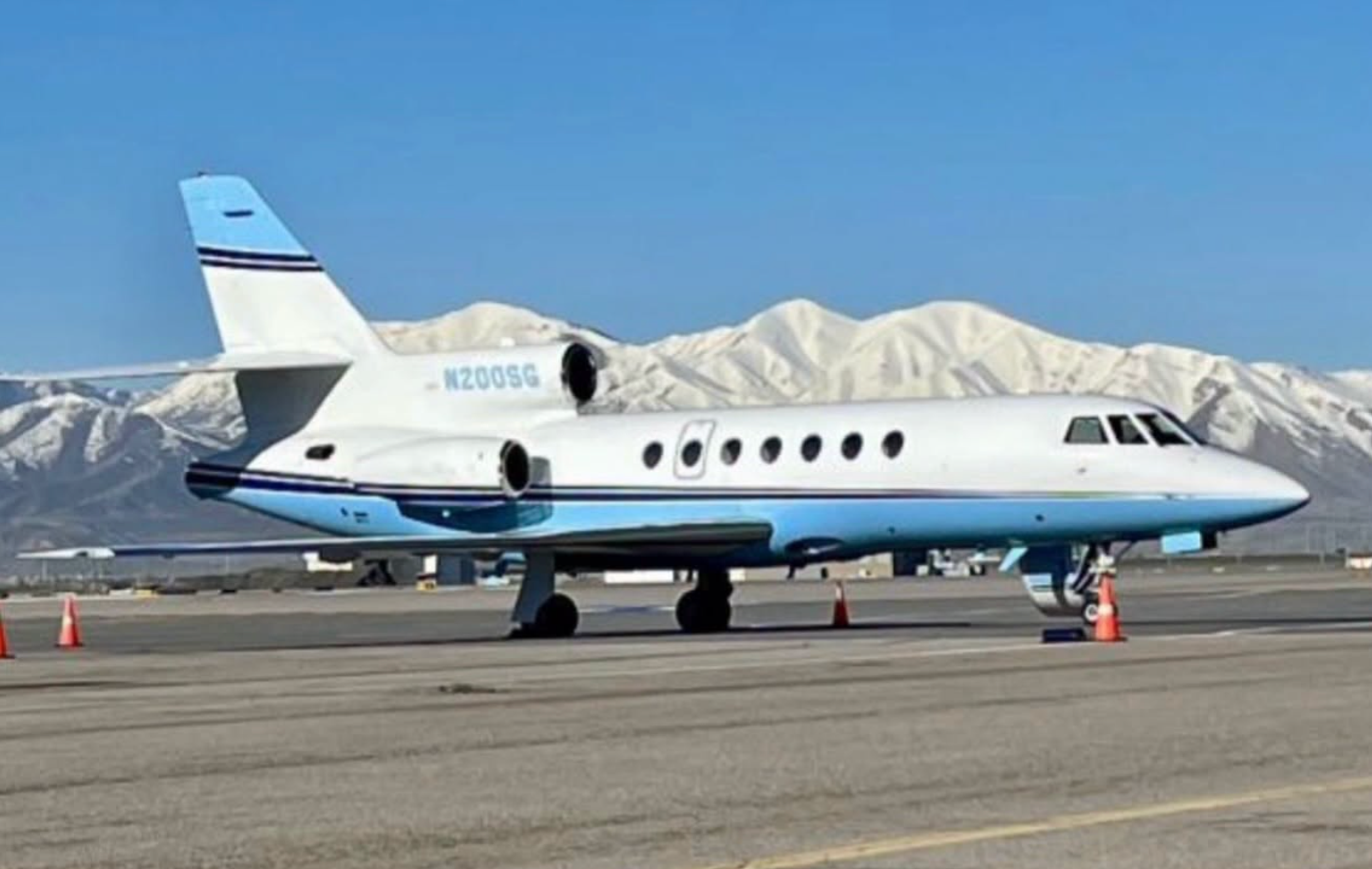 Dassault Falcon 50 N200SG parked on an airport apron with snow-covered mountains in the background.
