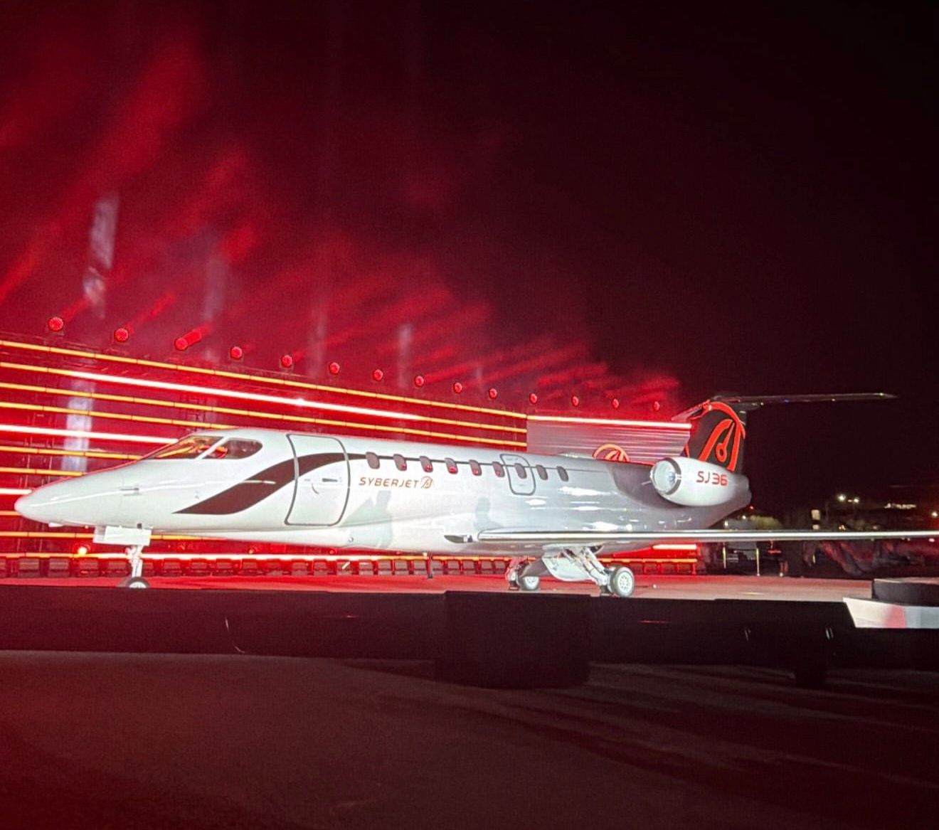 White SyberJet SJ36 mockup displayed under red stage lighting at its unveiling.