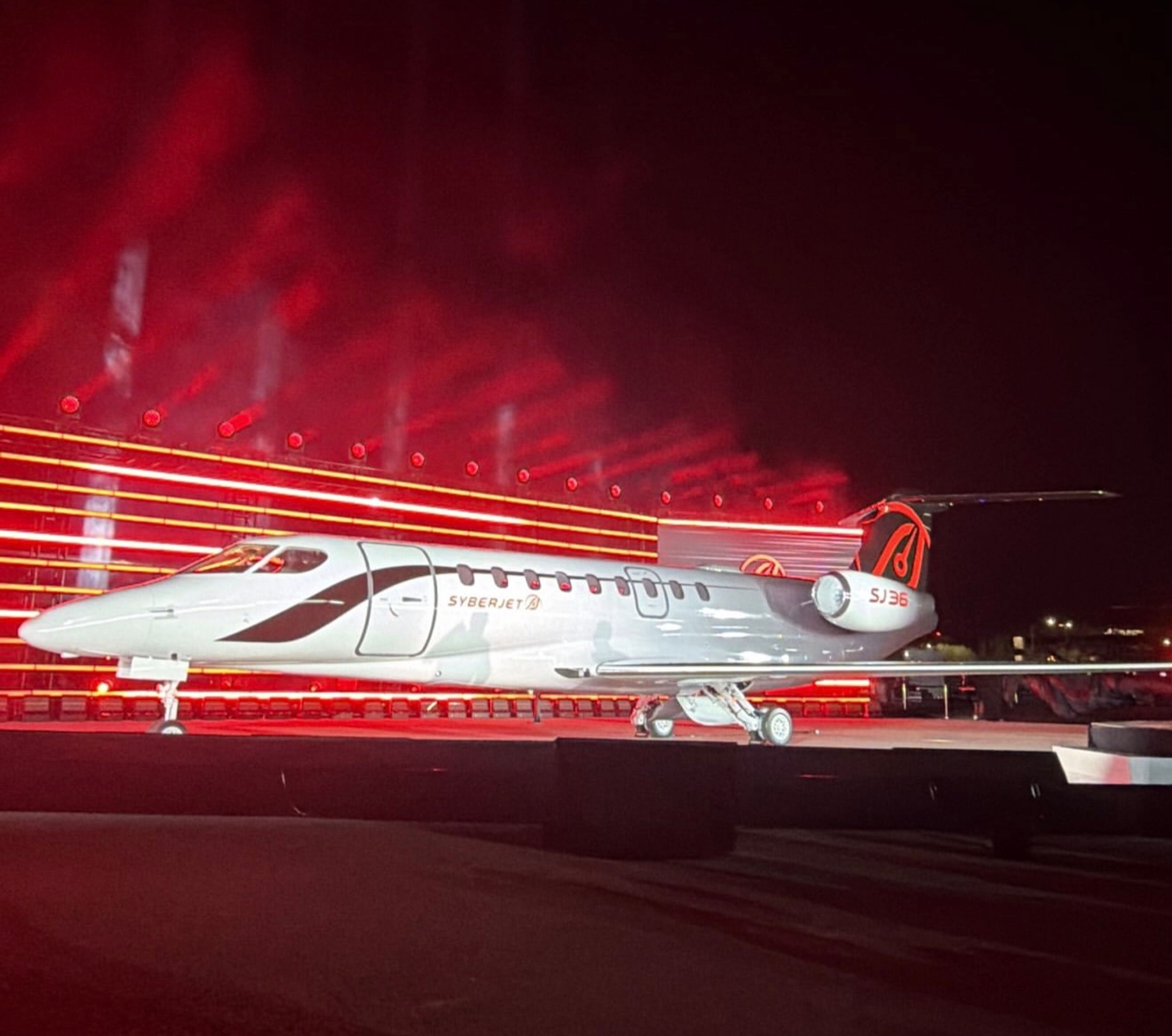 White SyberJet SJ36 mockup displayed under red stage lighting at its unveiling.