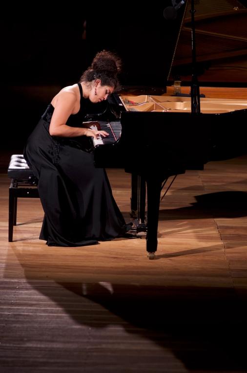 A woman playing the grand piano in a black long dress