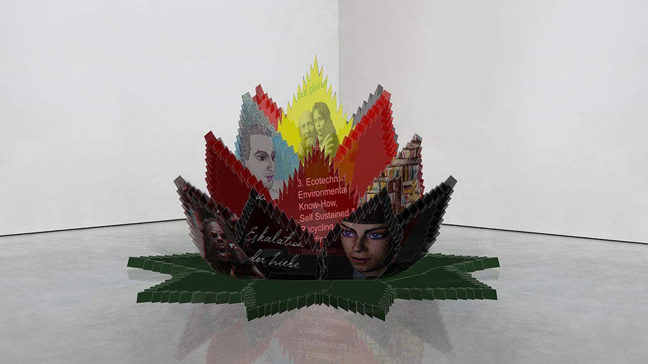 A digitally designed cacti plant-flower depicting images and text as leaves and placed in the corner of a white-wall room with cement floors.