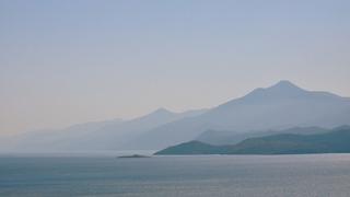 A photo of the Aegean Sea with the mountains of Turkey in fog in blue and grey colours