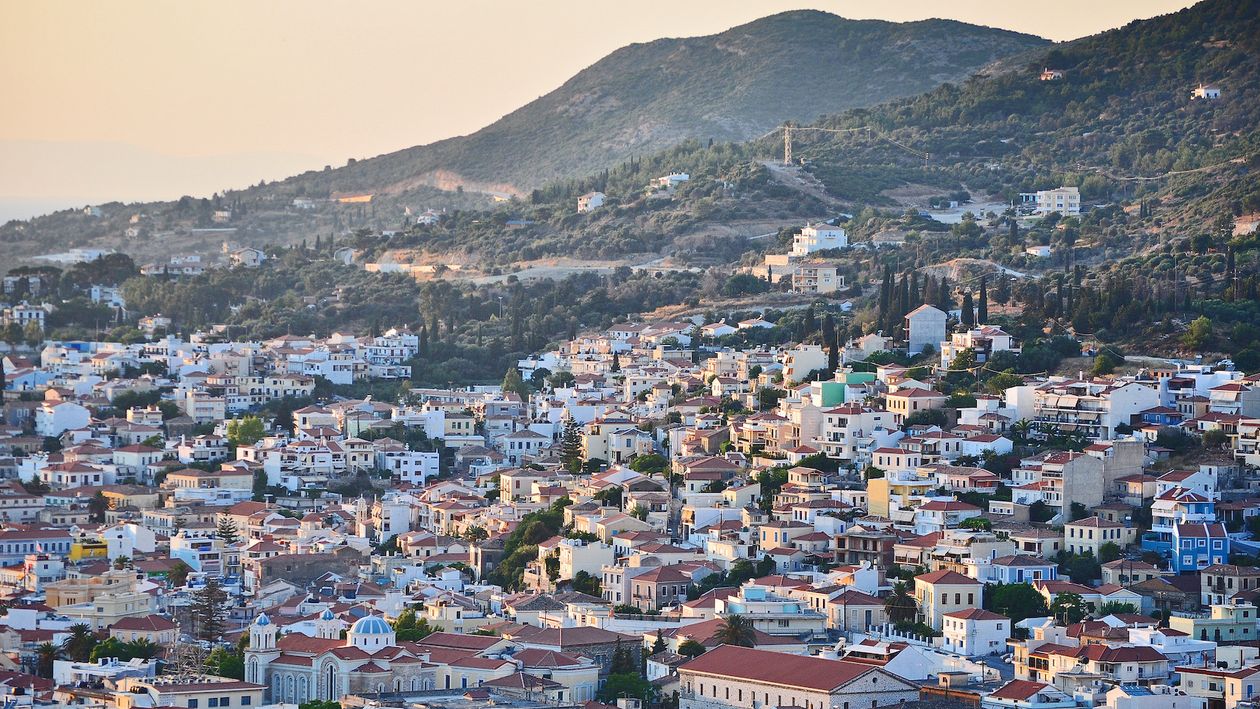 Overview of a greek small city built on an uphill with evening light
