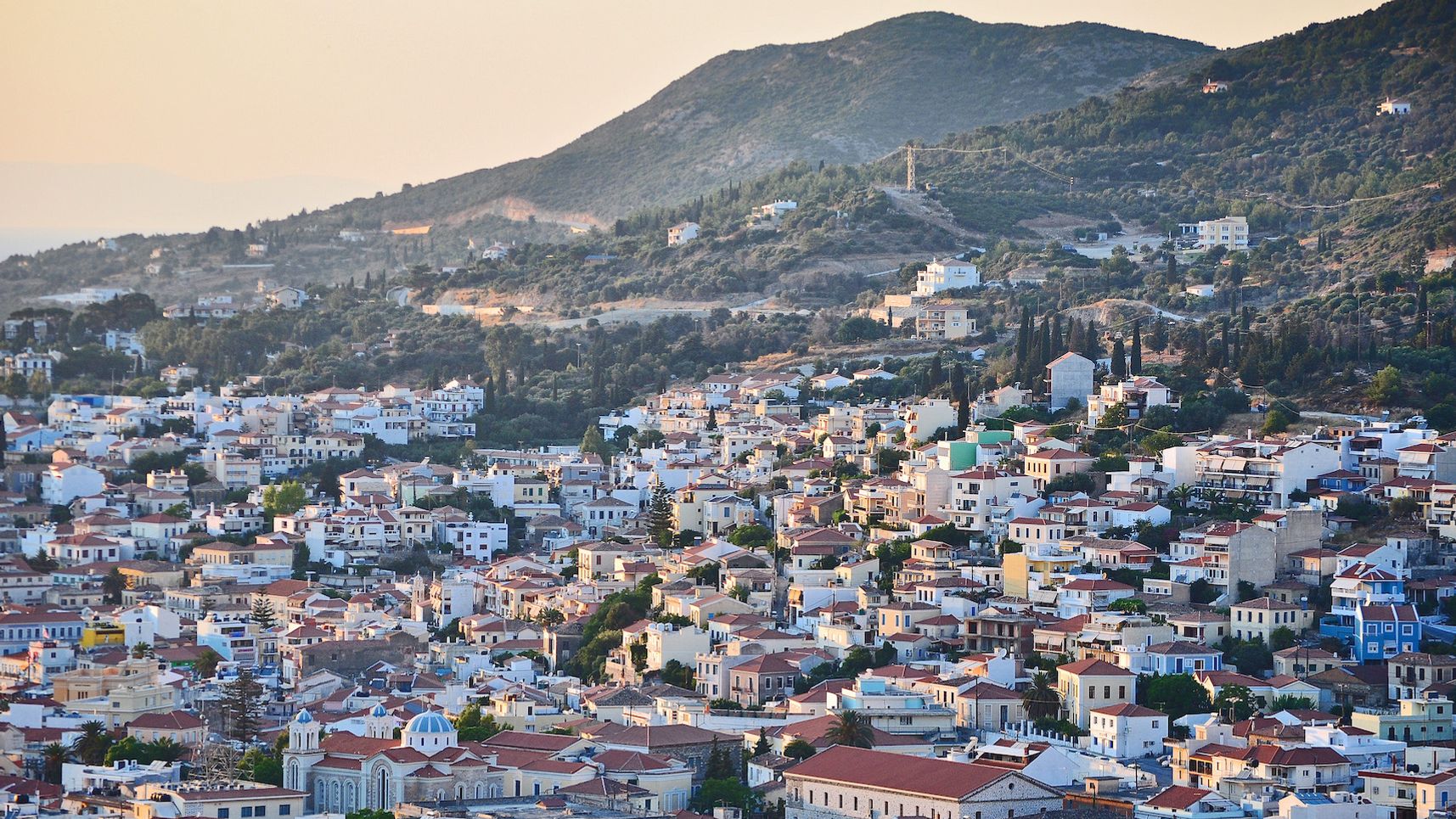 Overview of a greek small city built on an uphill with evening light