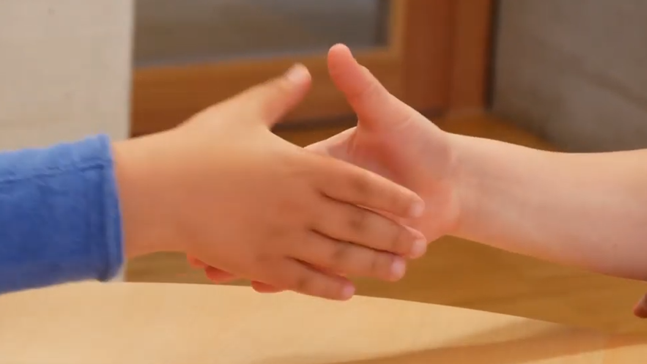 Close up of two hands of two children on the way to greeting each other