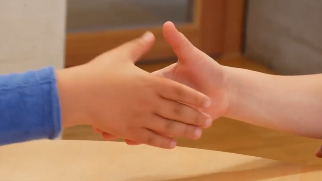 Close up of two hands of two children on the way to greeting each other