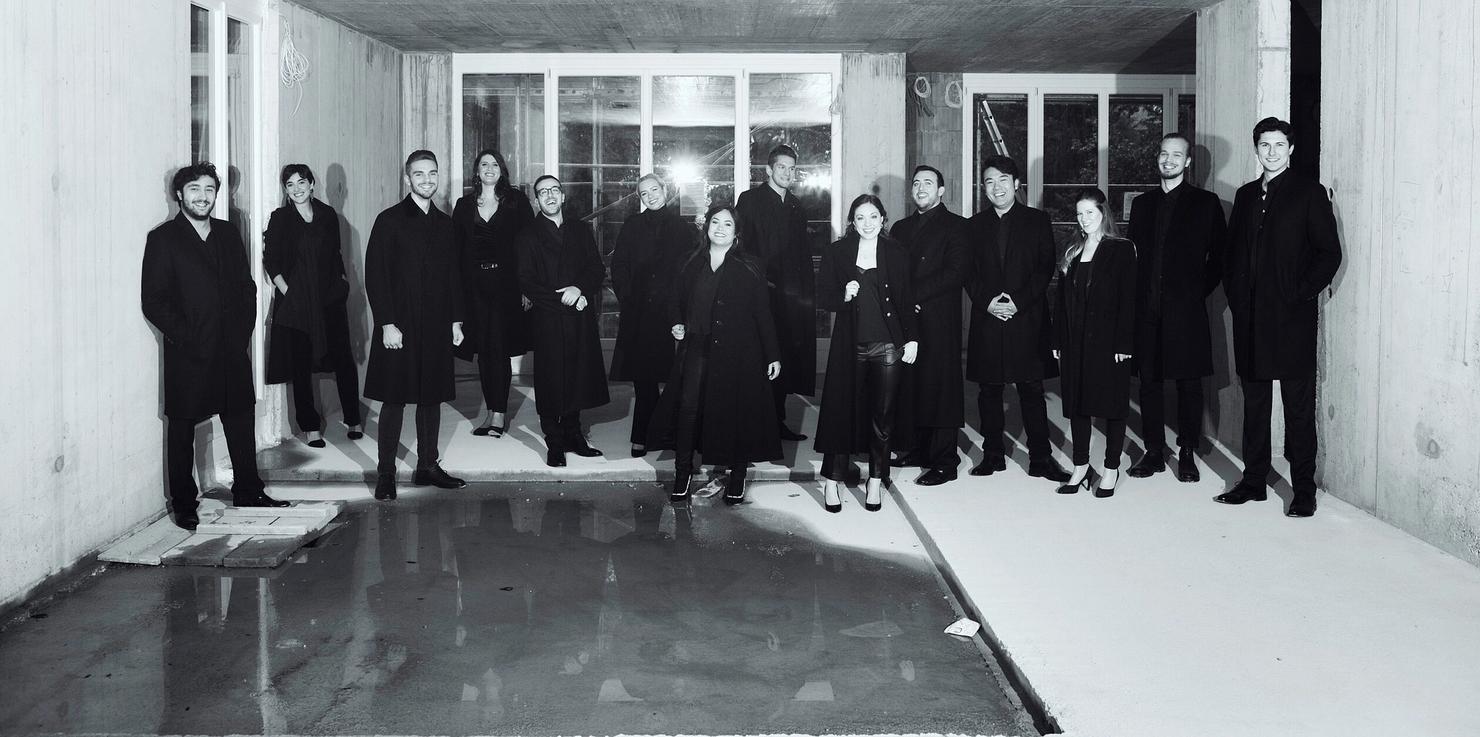 A black and white photo of 14 students in long coats