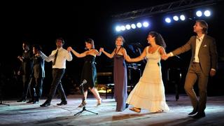 7 musicians on stage of the the Ancient Theatre of Pythagorion, standing in a row, holding hands