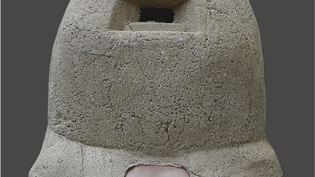 Porträt eines nackten Mannes. Sein Torso ist sichtbar, aber sein Kopf und seine Schulter sind unter einer helmartigen Struktur aus Kalkstein verborgen.