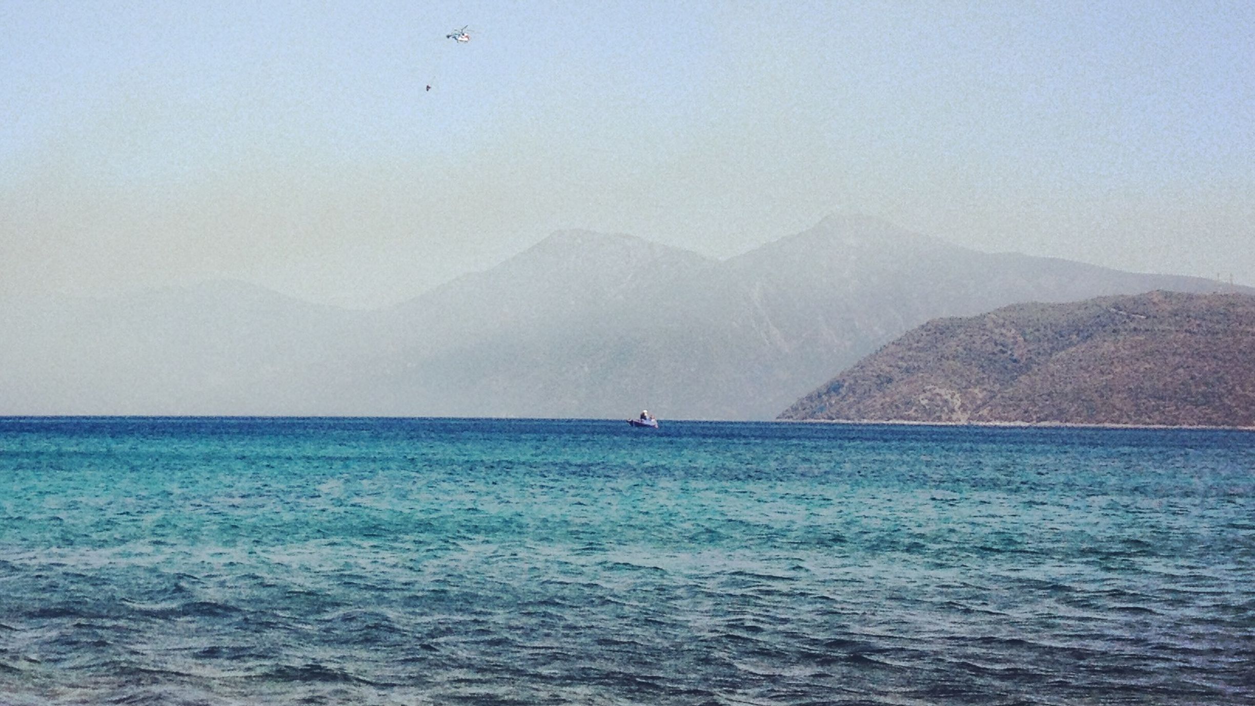 türkis-blaues, ruhiges Meer bis zum Horizont, hinterm Horizont Berge