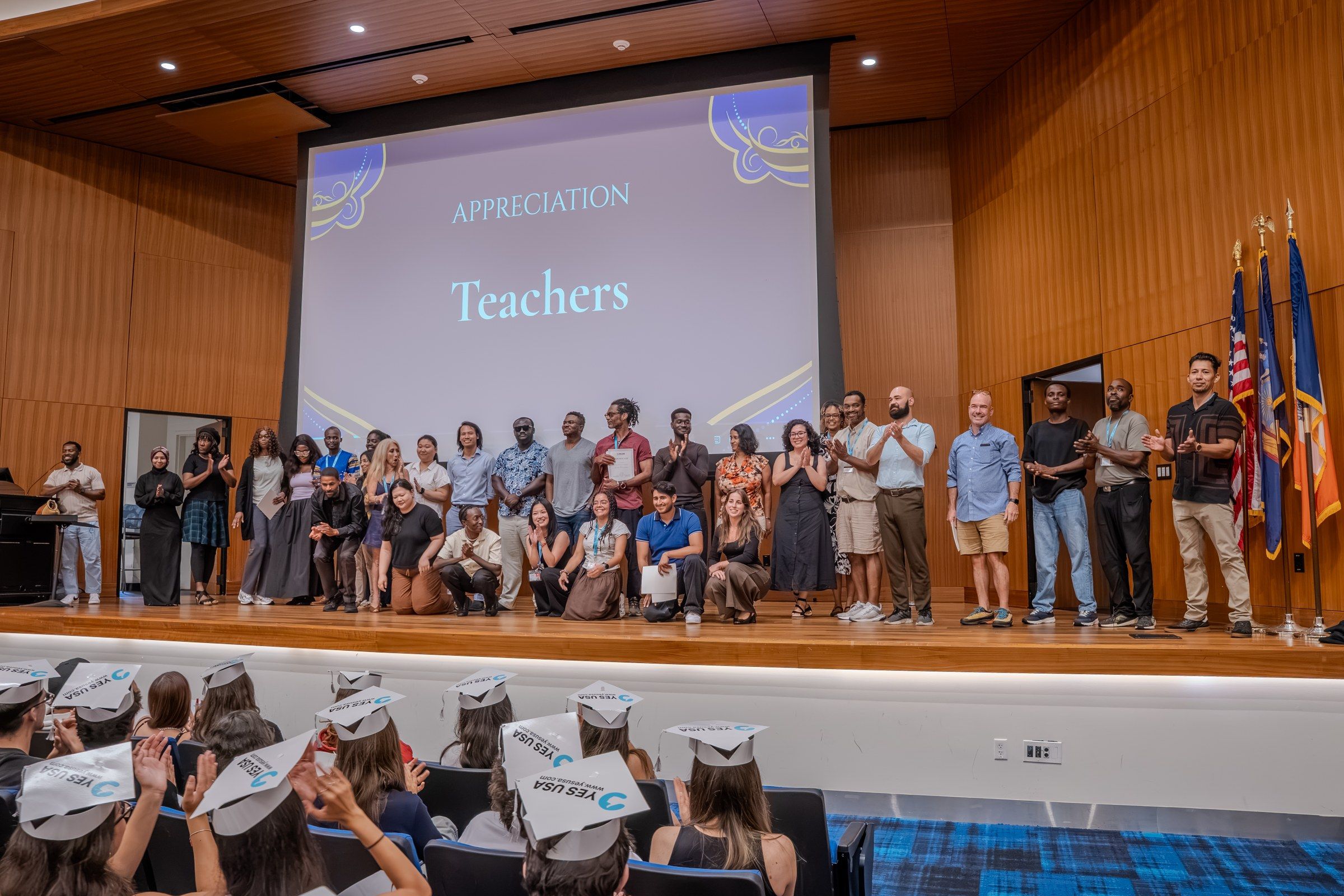 YES USA teachers on stage during the teacher appreciation at the St. John's graduation, with graduates in caps in front