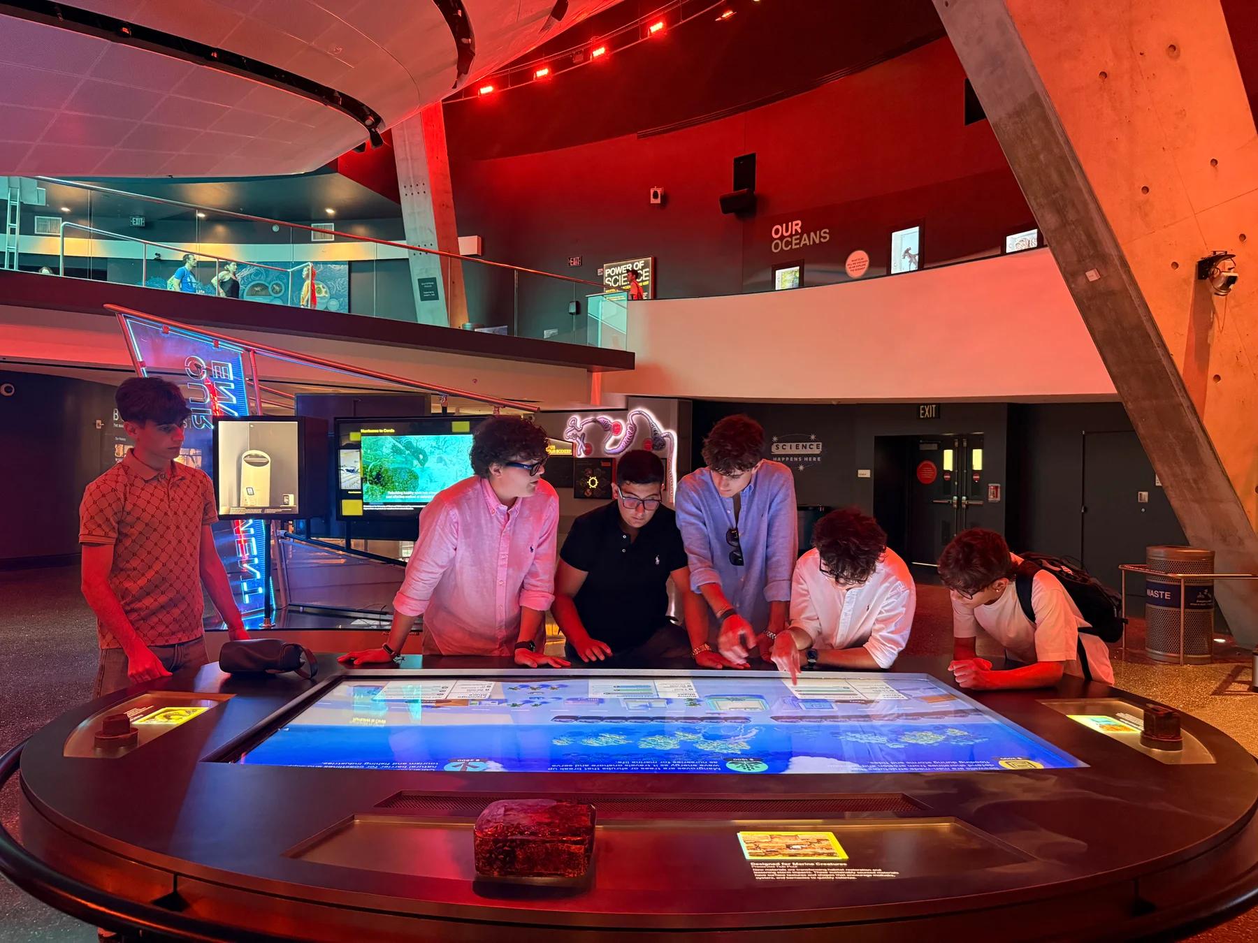 Students gathered around an interactive science exhibit