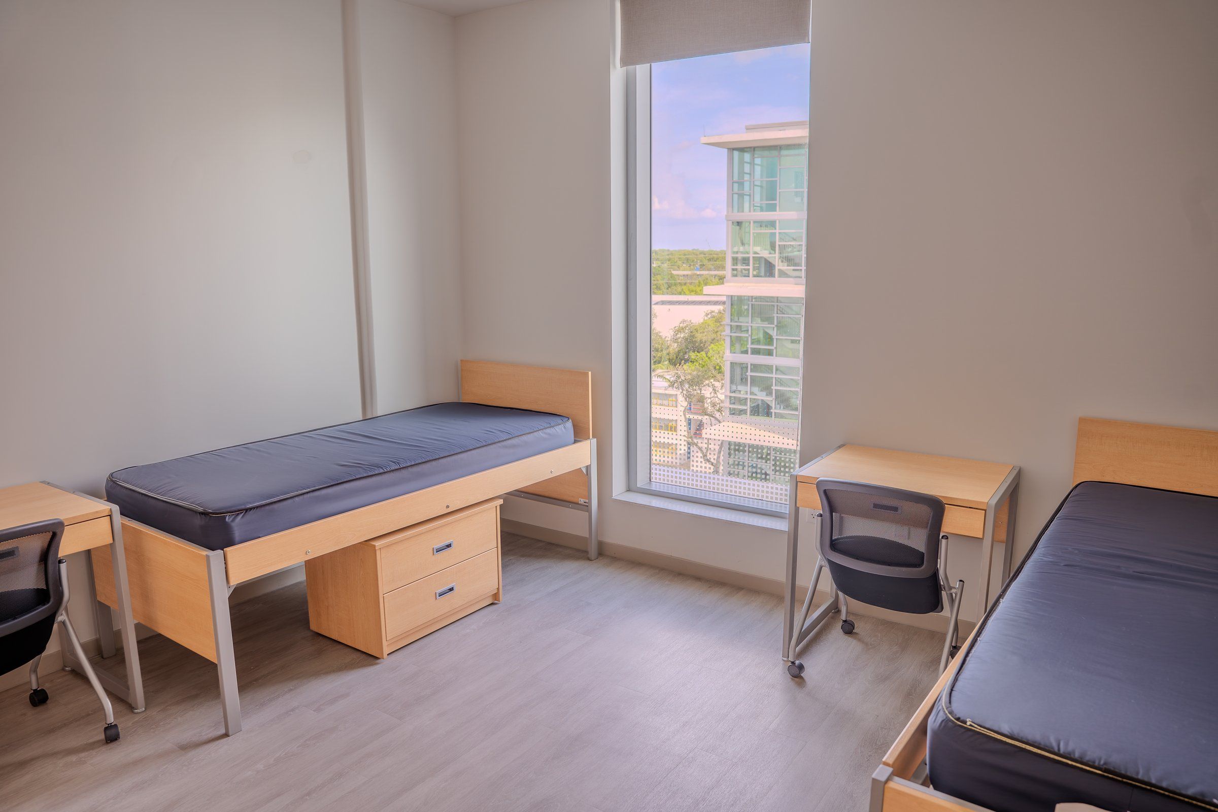 Twin beds and desks in a bright University of Miami residence room
